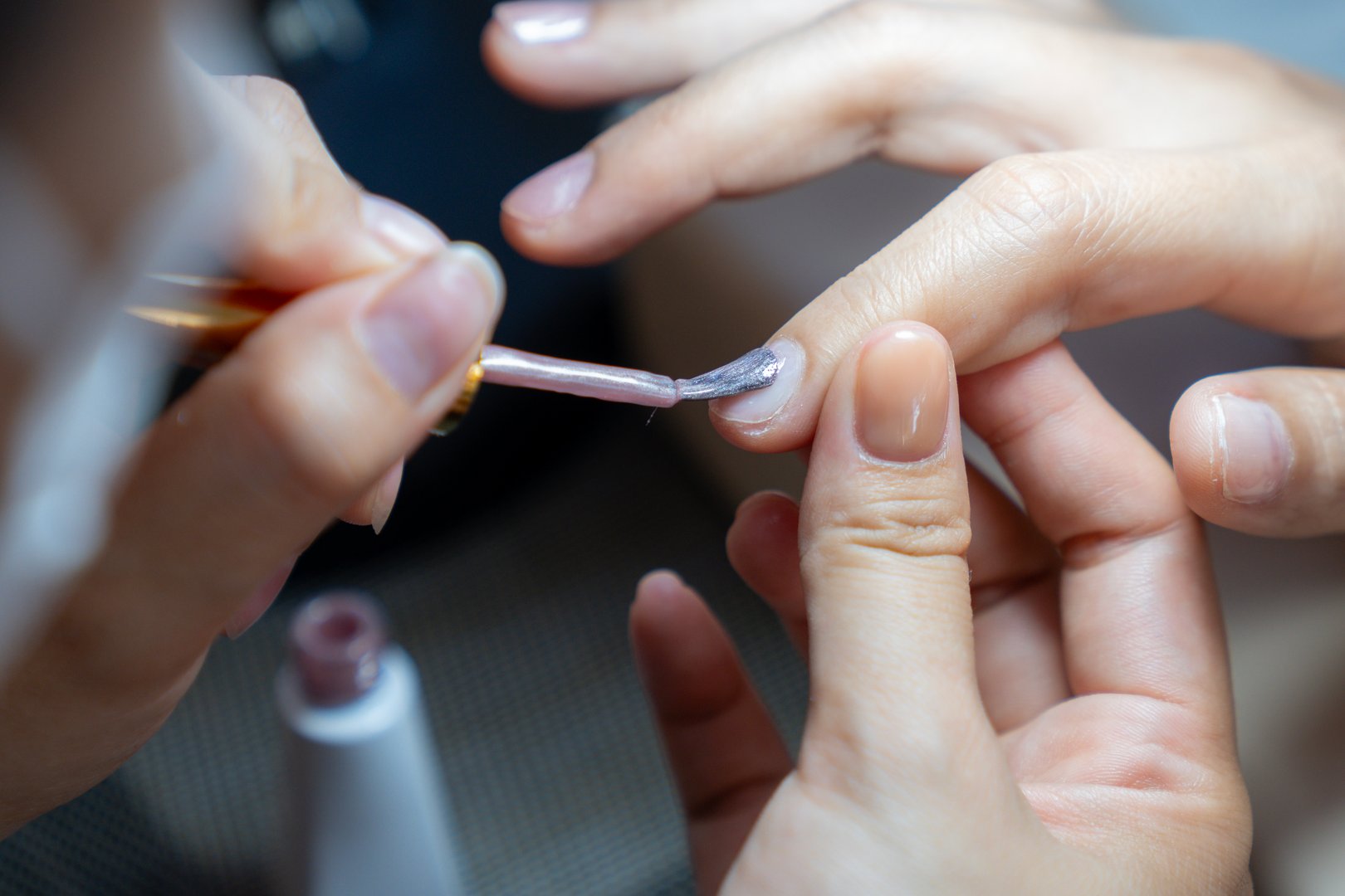 The manicure coats nails with gel polish in the beauty salon.