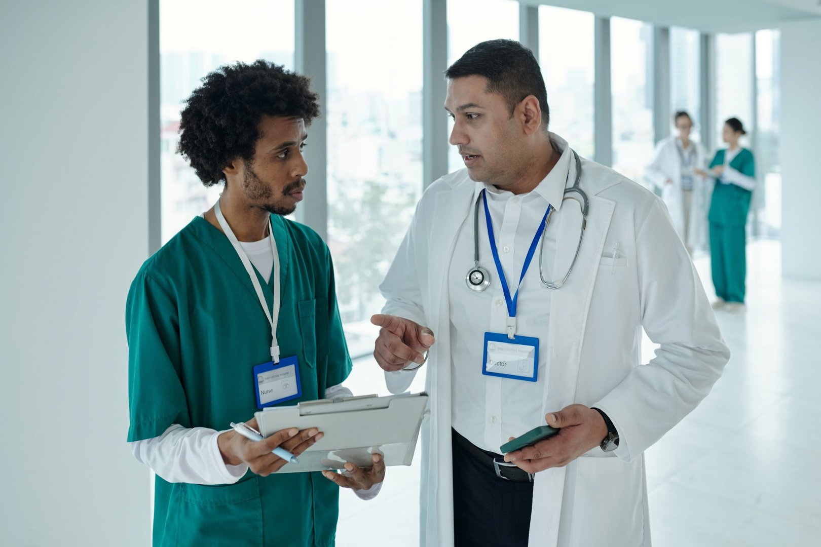 Doctor in white coat discussing diagnosis with colleague while standing in corridor