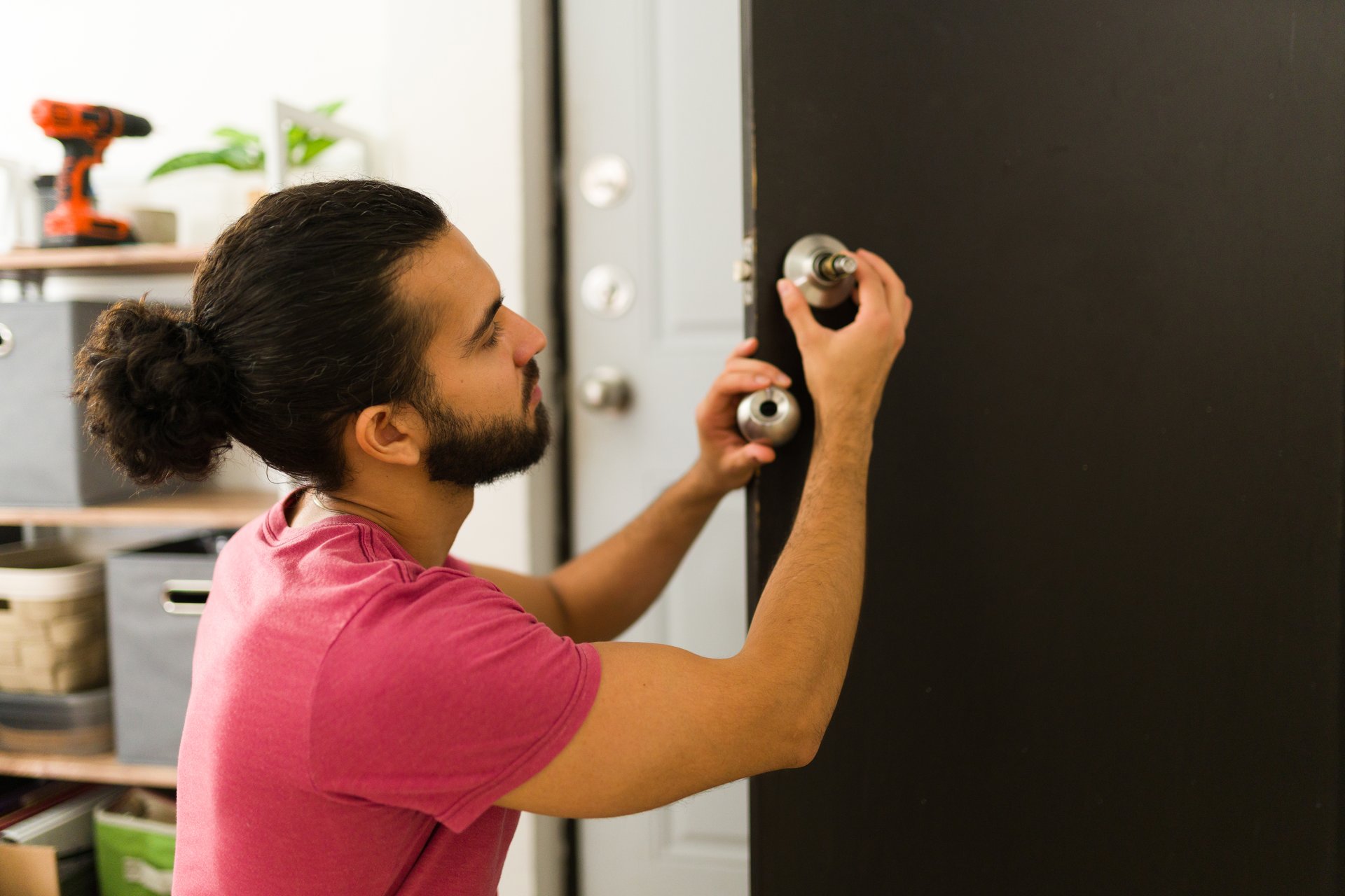 Young handyman fixing a door lock in a house, performing home repairs and maintenance as a diy project