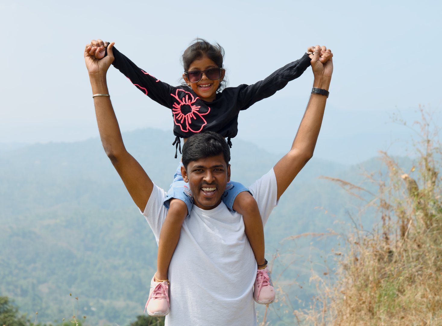 A heartwarming image of a father and daughter sharing a special moment on the peak of a mountain. Capture the joy