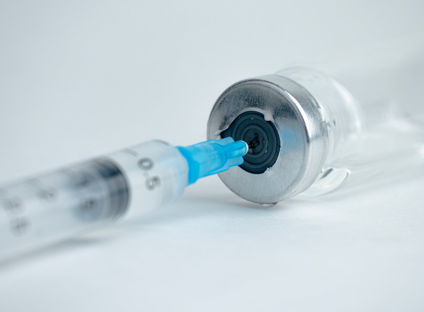 A syringe is inserted into a vial, drawing liquid into the syringe for use
