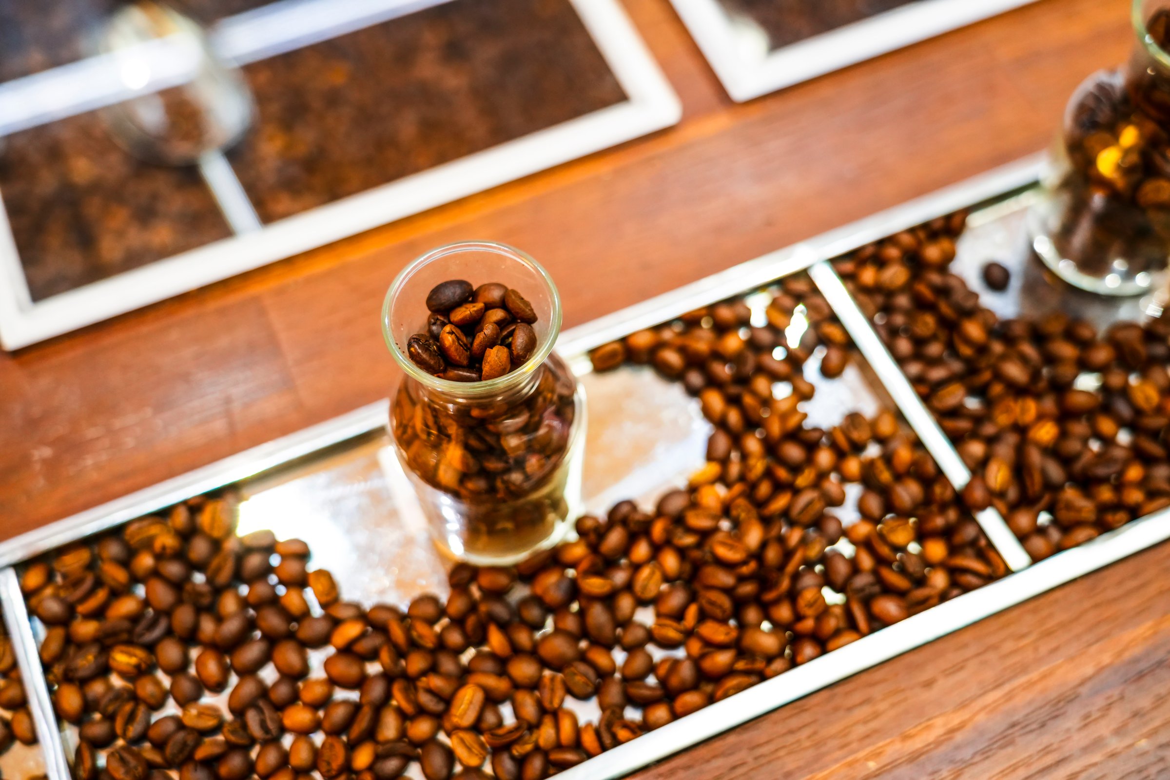 Spilled roasted coffee beans in glass cups on the counter.