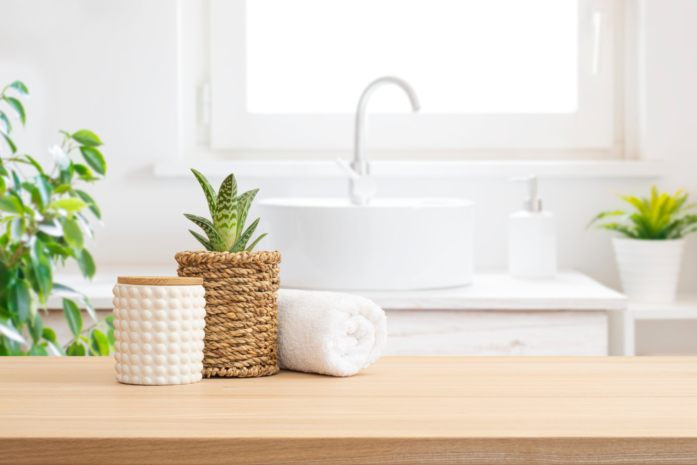 Spa decor products composition on wooden table in blurred bathroom interior background