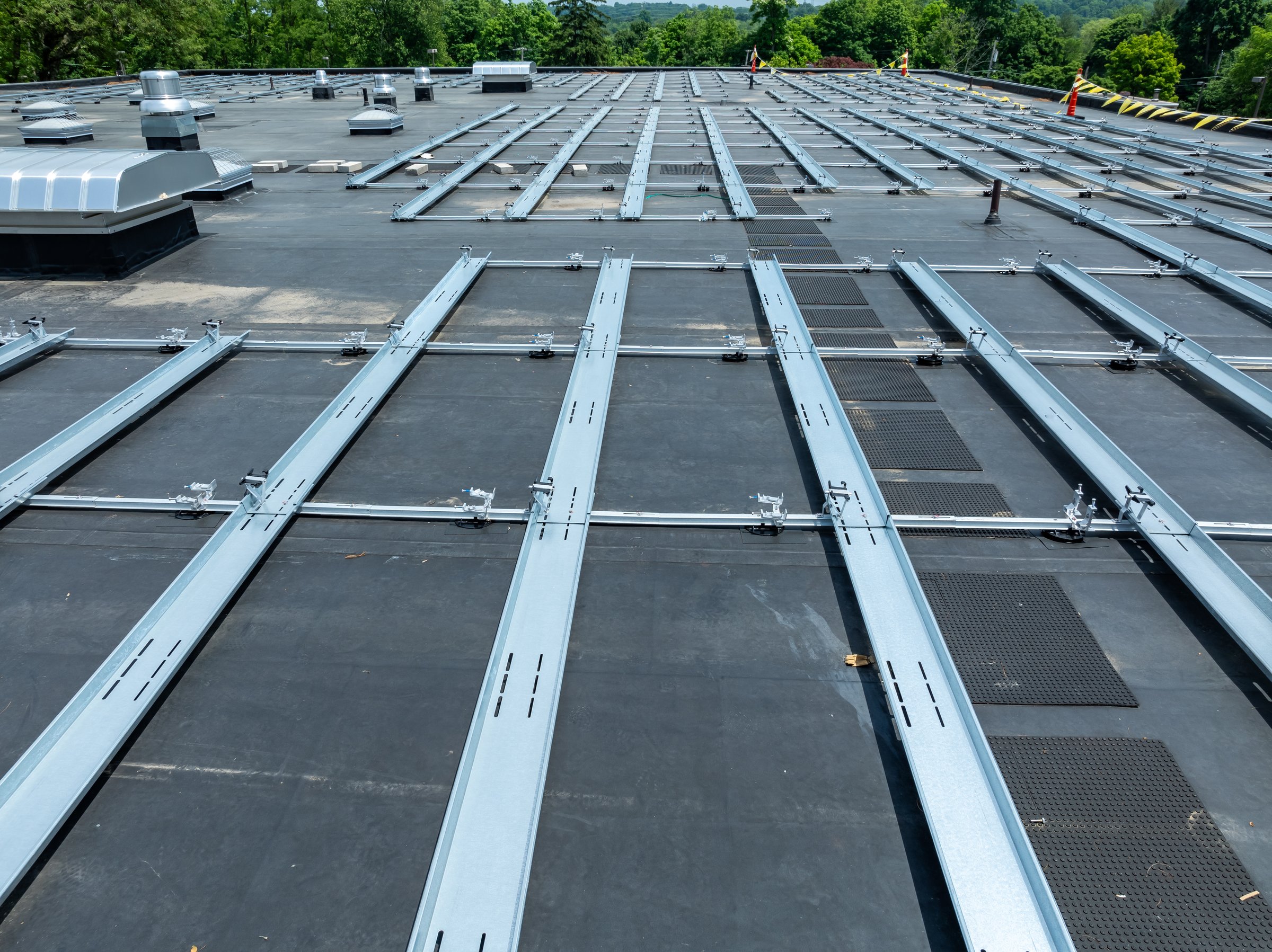 Photo of framing and concrete block ballast blocks for new solar panels being installed on a flat commercial, industrial EPDM roof.