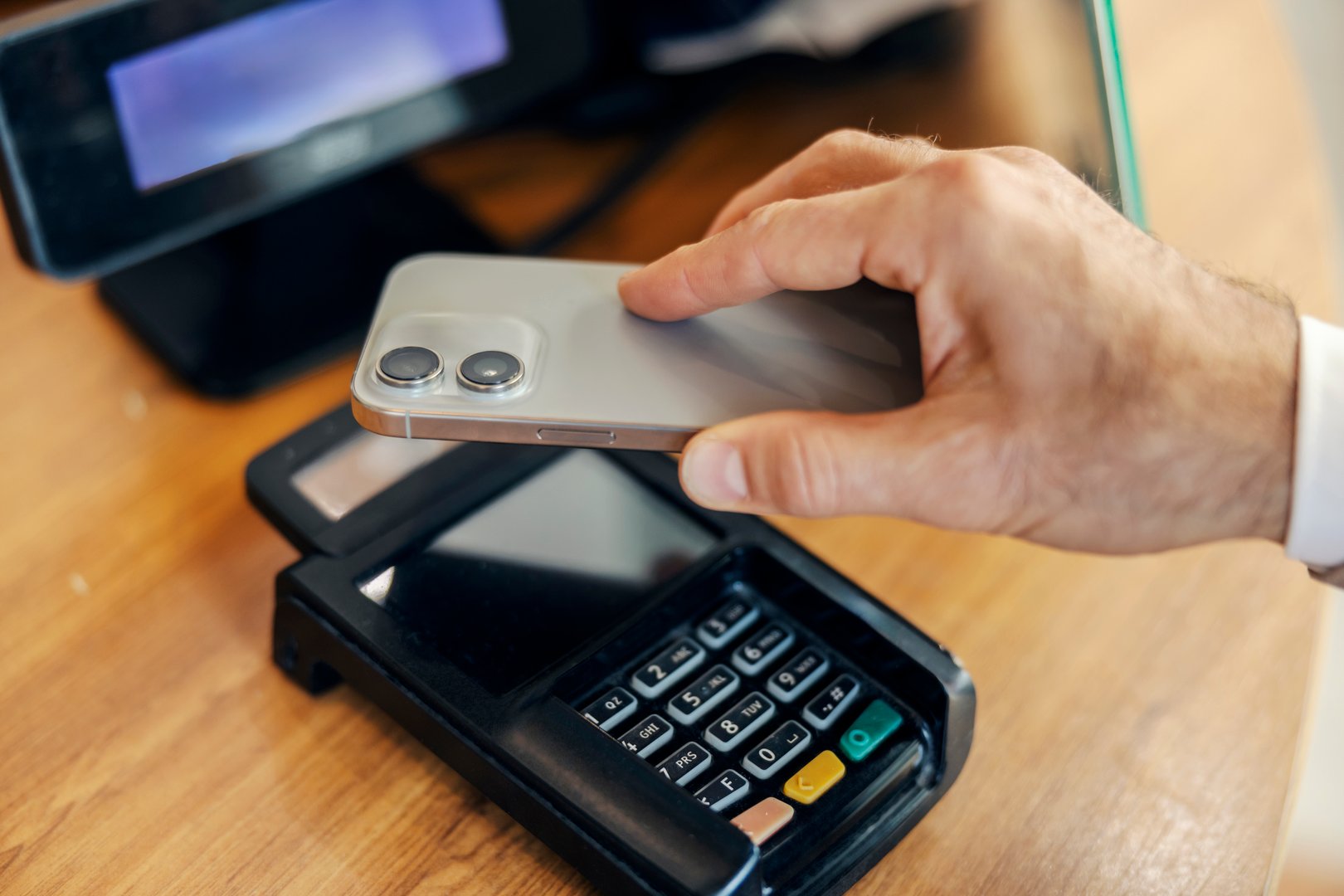 Person using a mobile phone to make a secure and fast contactless payment at a point of sale terminal in a store