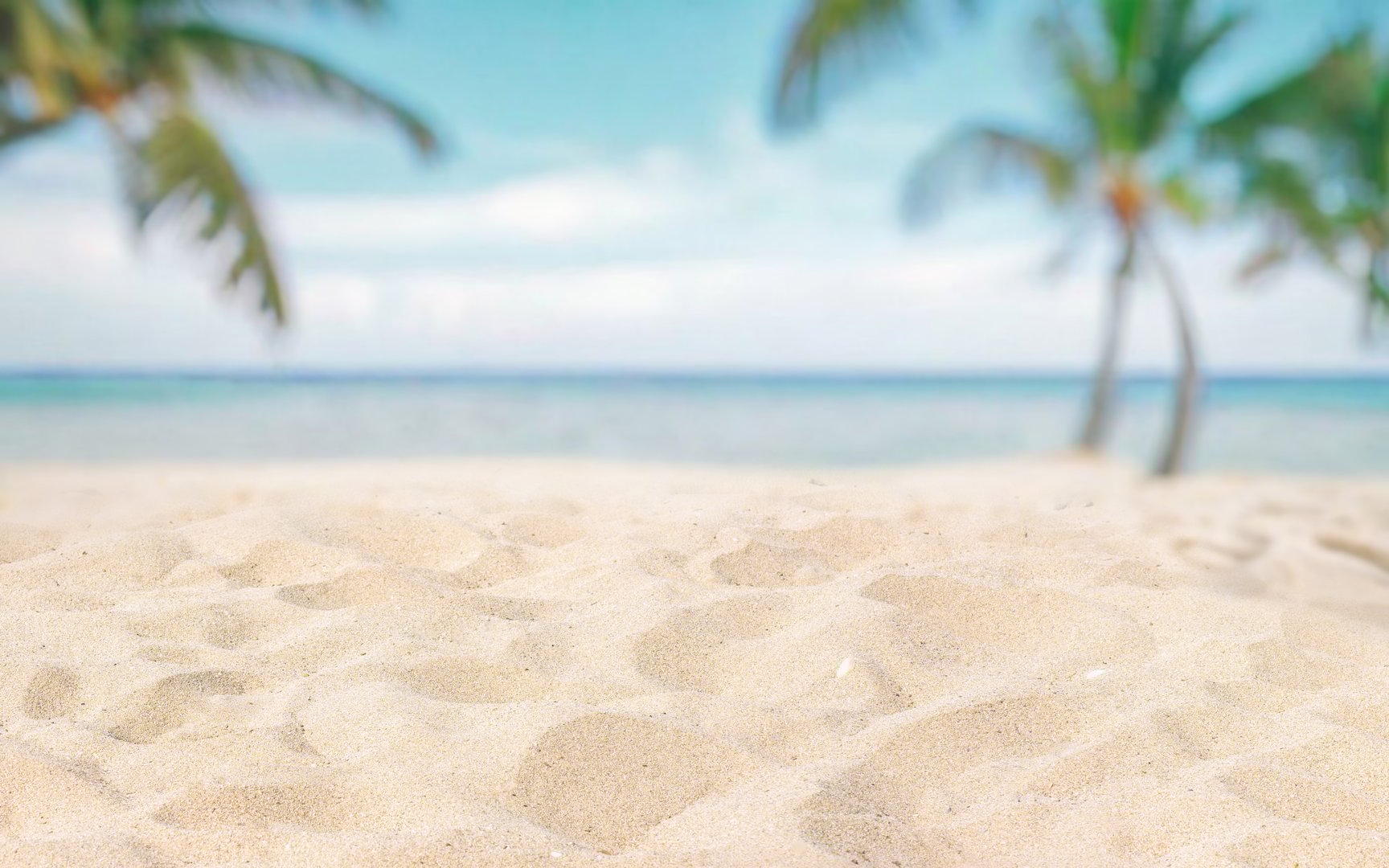 Abstract blurred defocused beach background, nature of tropical summer beach. Golden sand beach, sea water and palms against sky. Summer vacation concept.