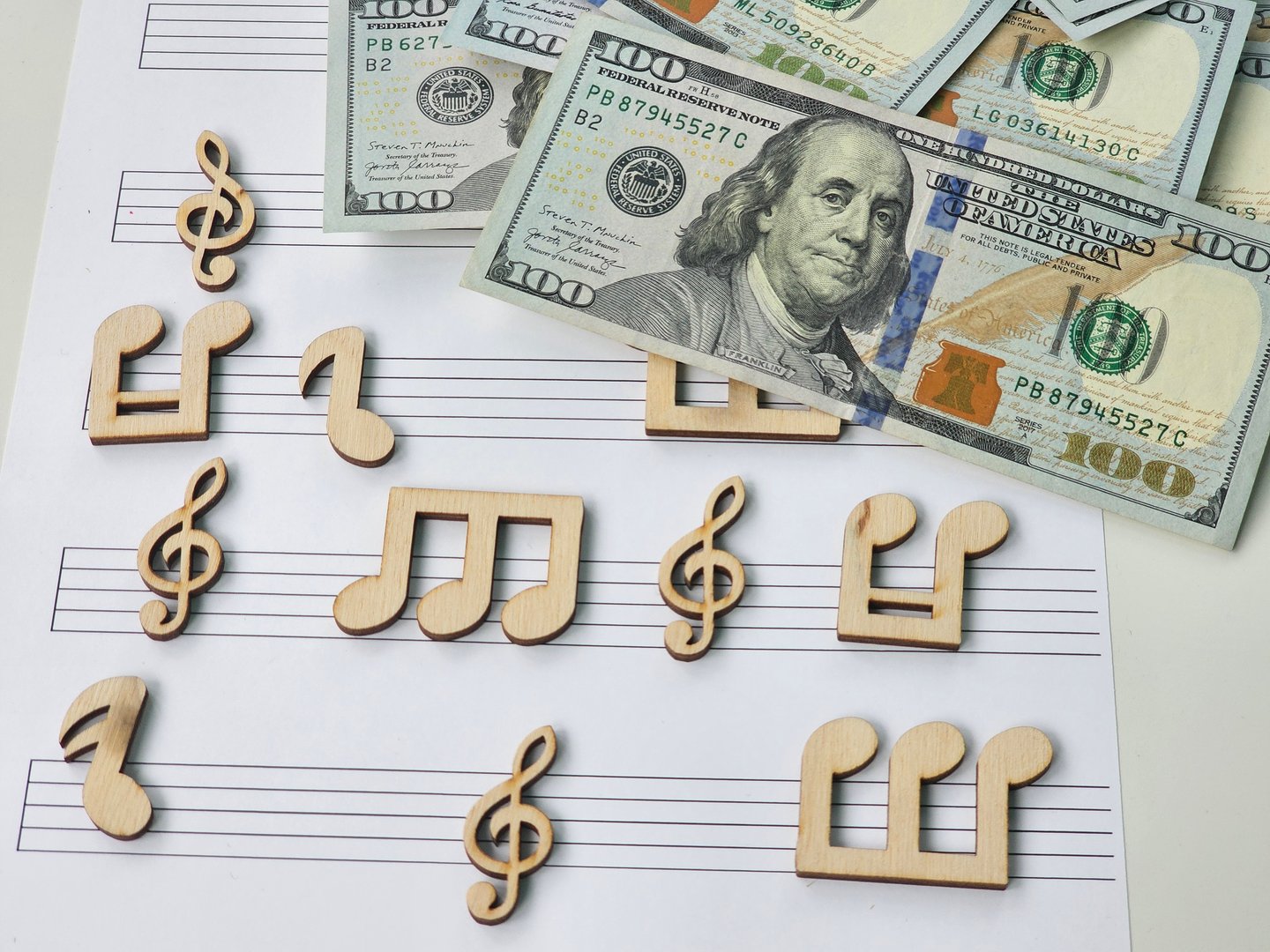 Musical notes alongside hundred dollar bills create a unique blend of art and currency in a creative setting