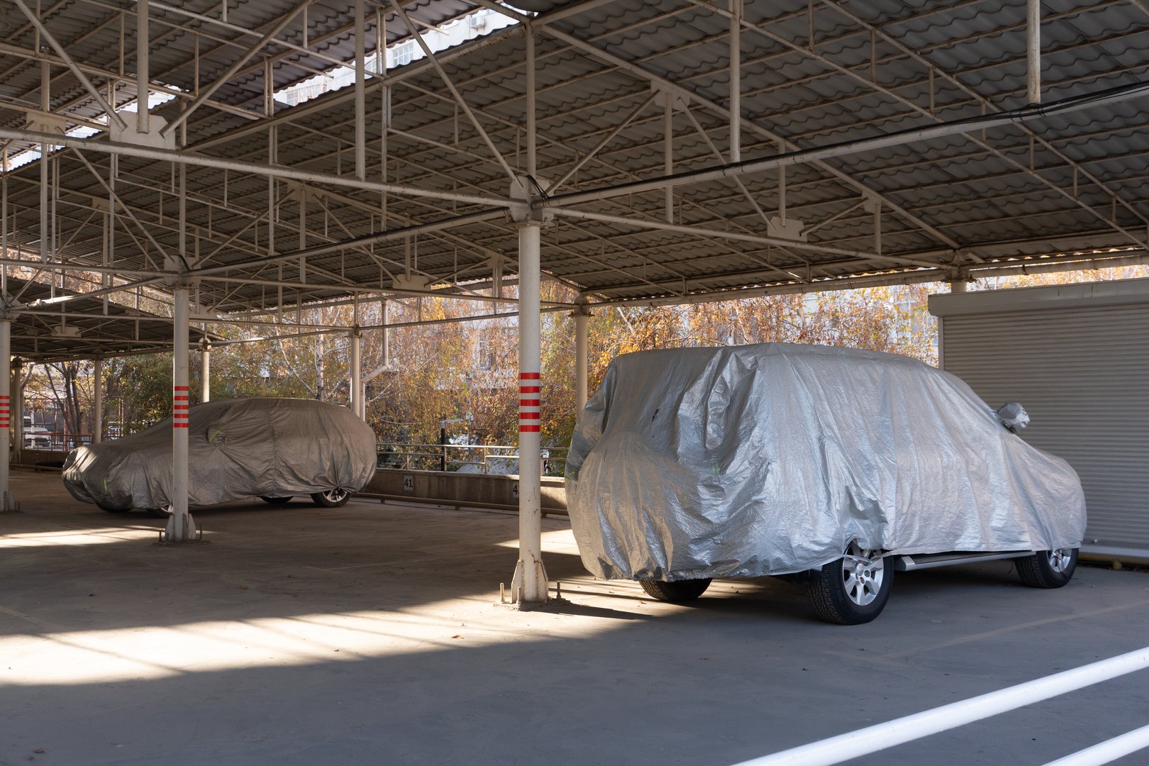 سيارات متوقفة تحت مظلة معدنية محمية بأغطية واقية