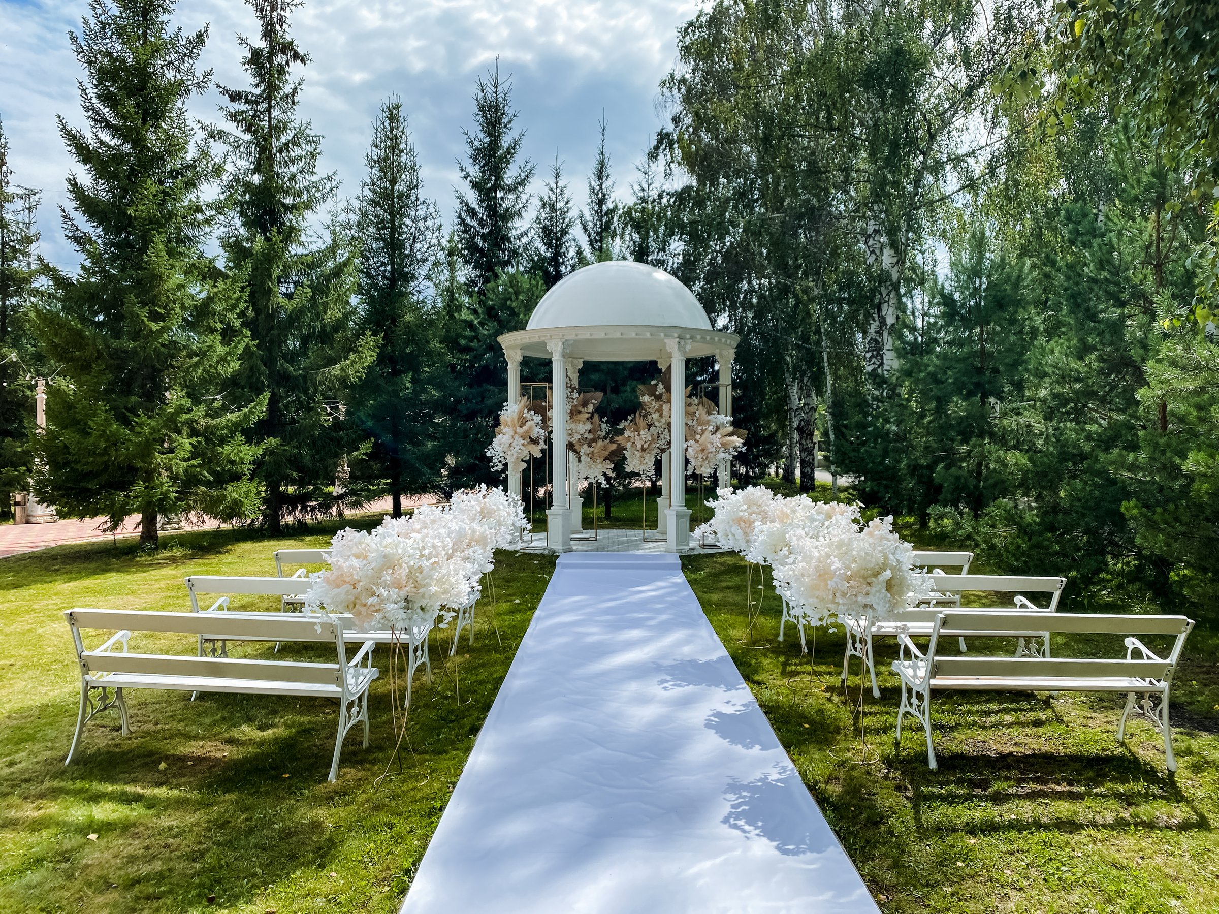 A beautiful wedding in a picturesque park features a charming gazebo and cozy benches, offering guests a lovely place to celebrate this special day filled with love, joy, and unity