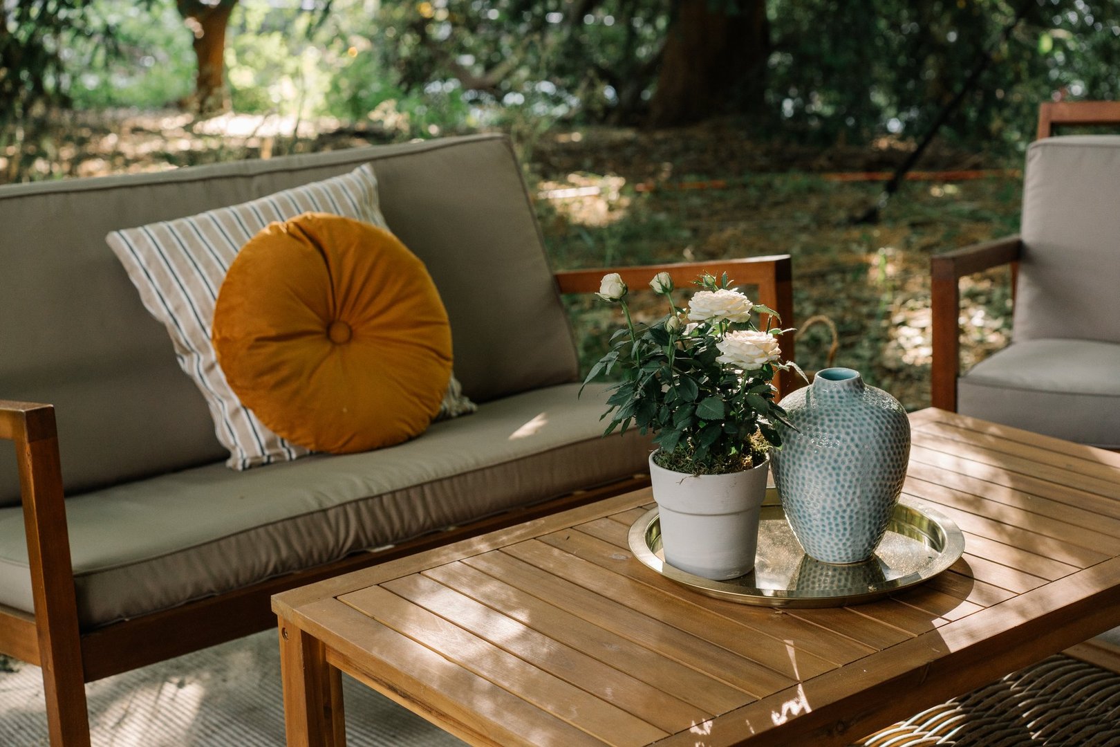 Modern outdoor patio furniture including table, chairs and sofa with cushions in garden setting