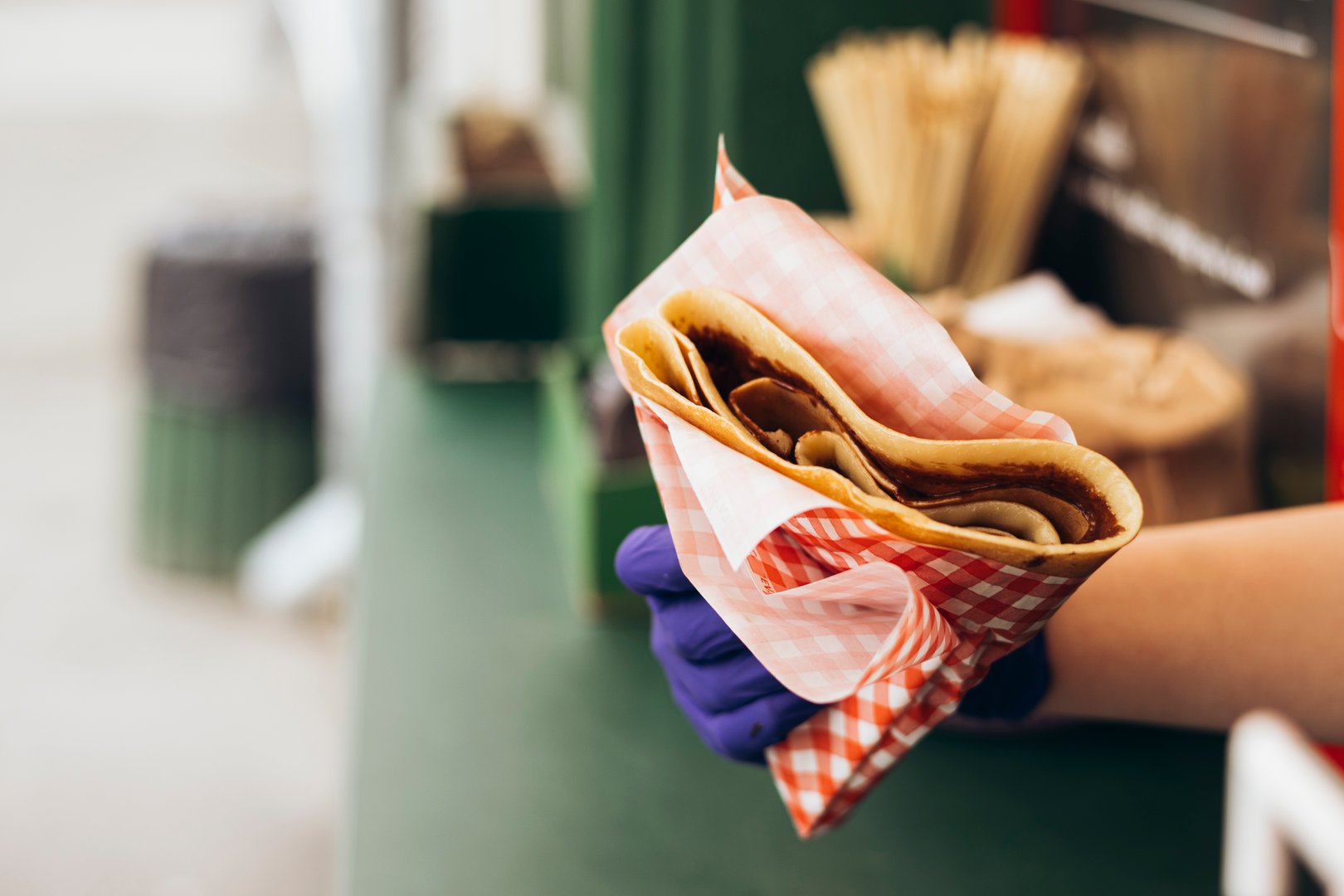 Woman holds a fresh crepes pancake in a disposable package. Concept of takeaway fast food and French street cuisine. Copy space.