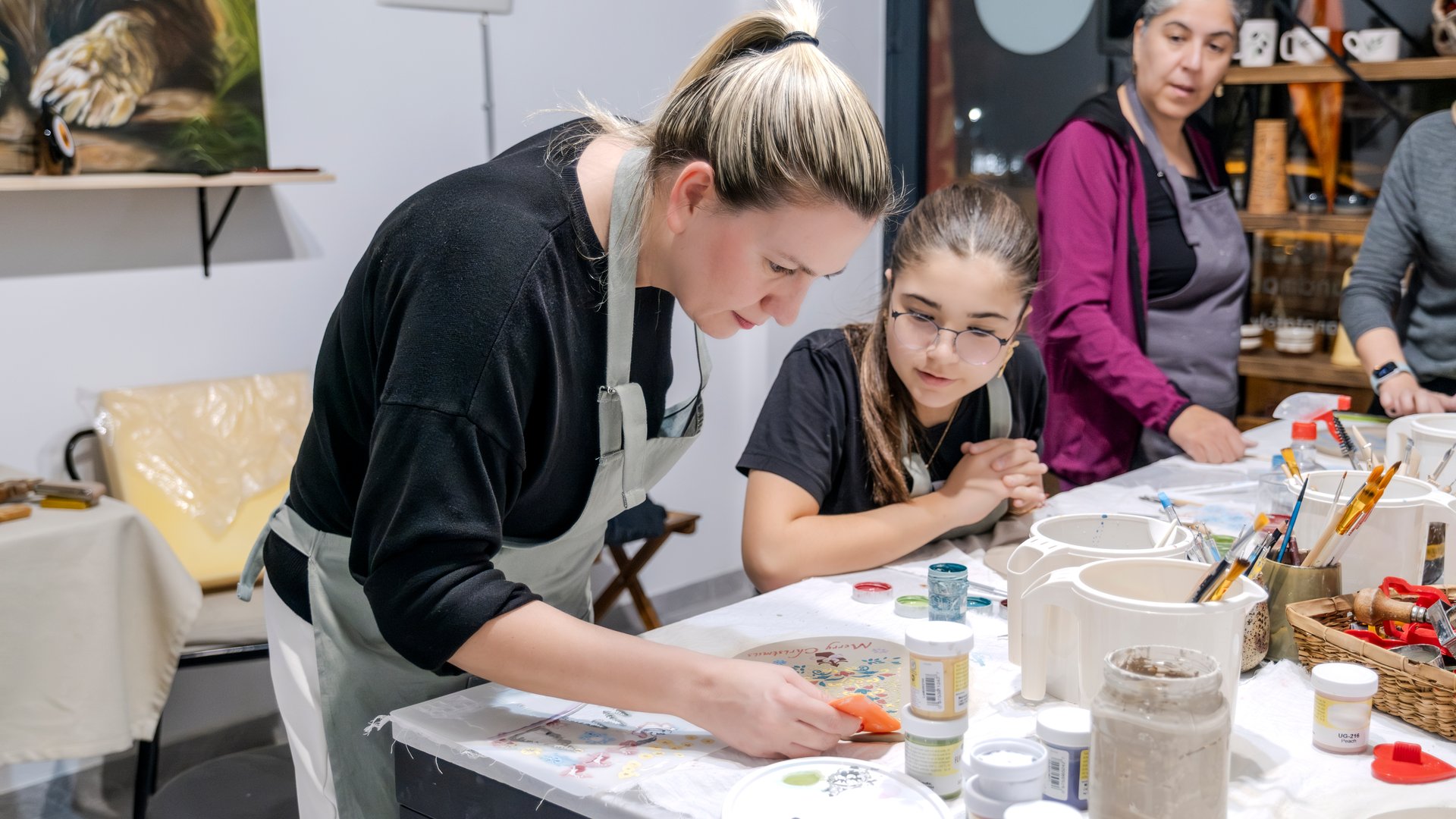 A mother and her daughter learning clay shaping at an art event