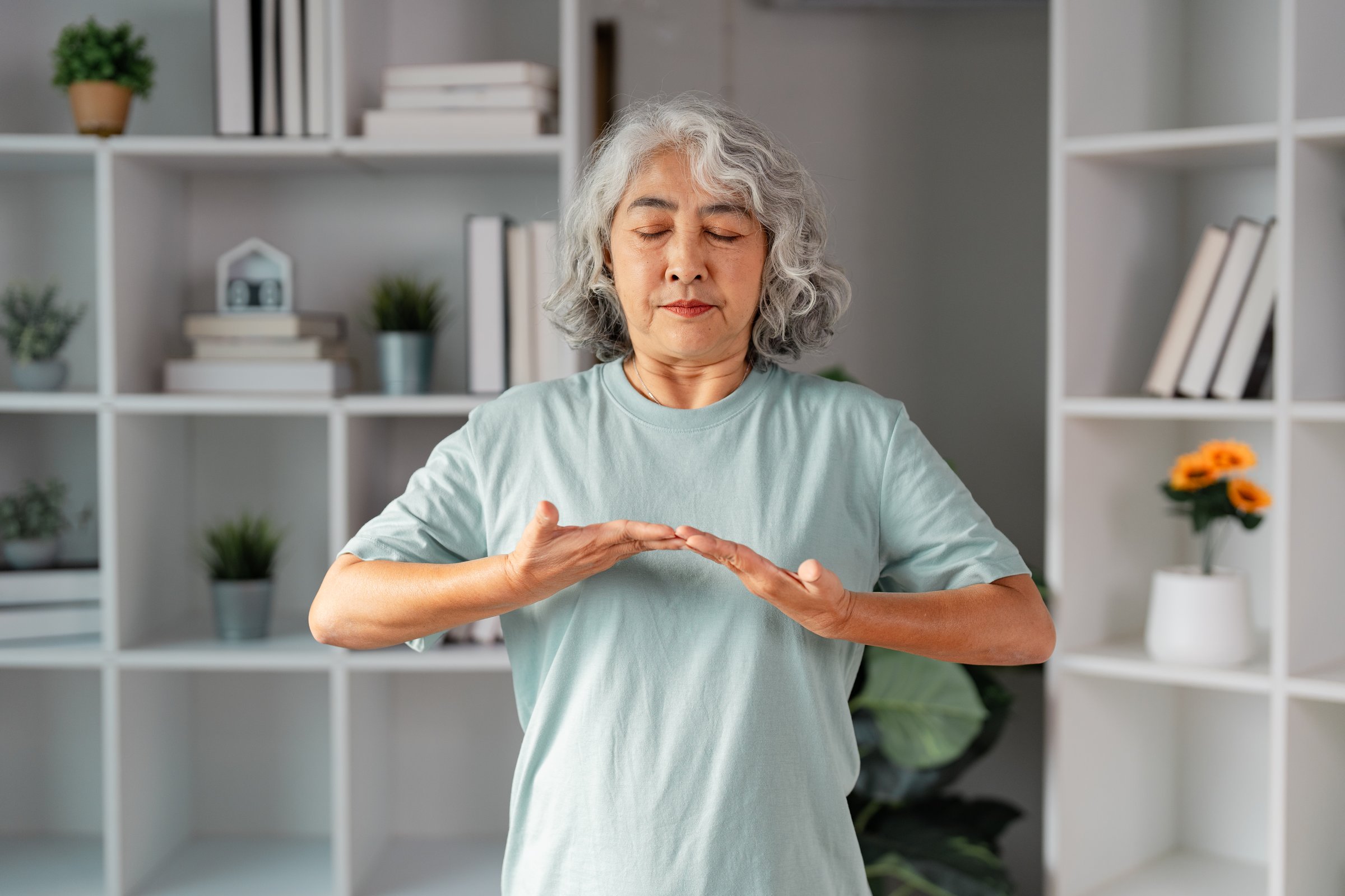 A senior woman engages in mindful breathing exercises at home, showcasing her commitment to wellness, health, and tranquility in daily life for emotional eating recovery