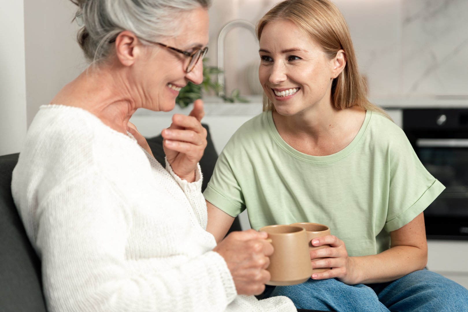 Elderly mother and adult daughter enjoying coffee together