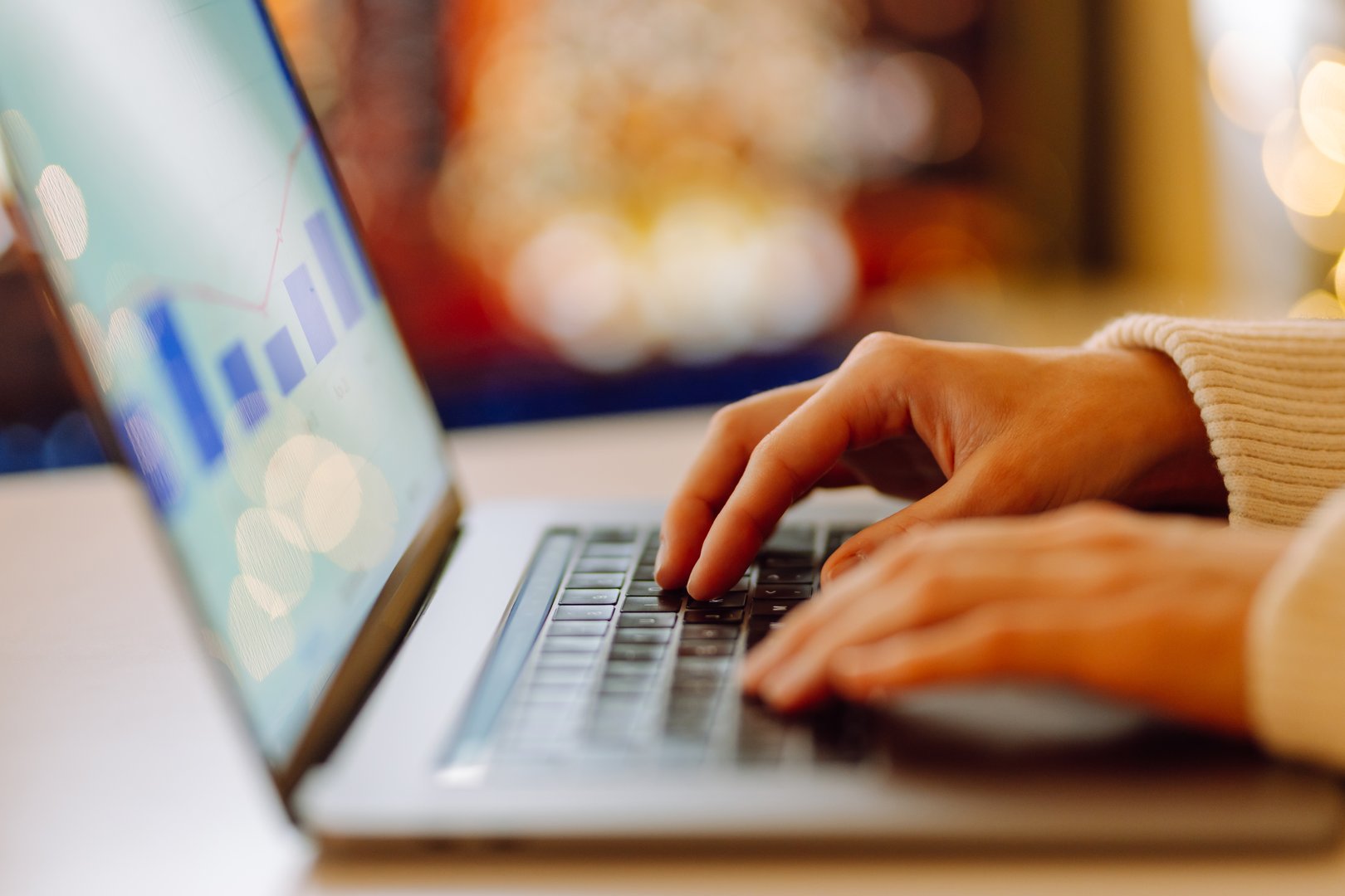 Close-up of a young woman's hands typing on a laptop. Female freelancer typing or working on a laptop in a cozy room. Freelancing concept, remote work.