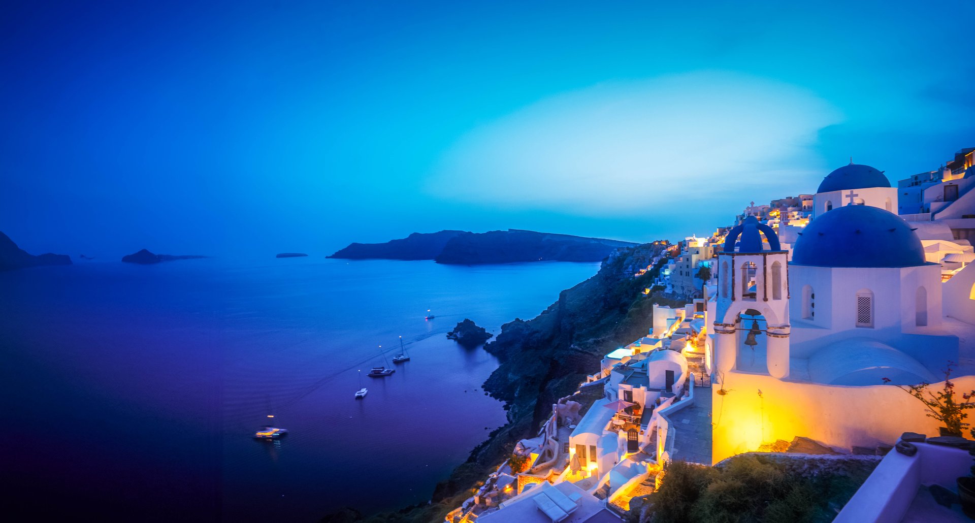 traditional greek village Oia of Santorini, with blue domes of churches and village roofs at night, Greece