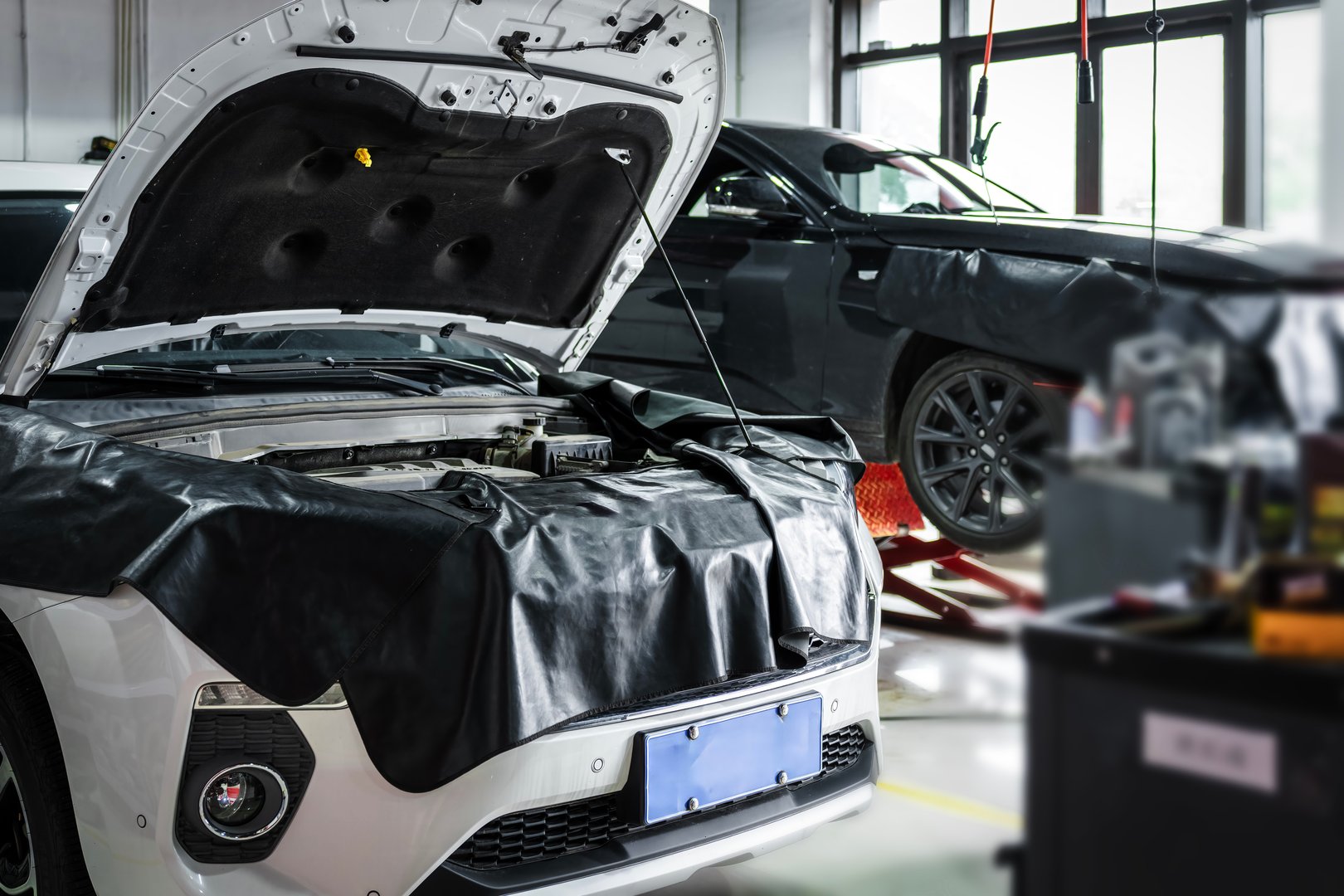 Car with open hood being serviced in an auto repair shop