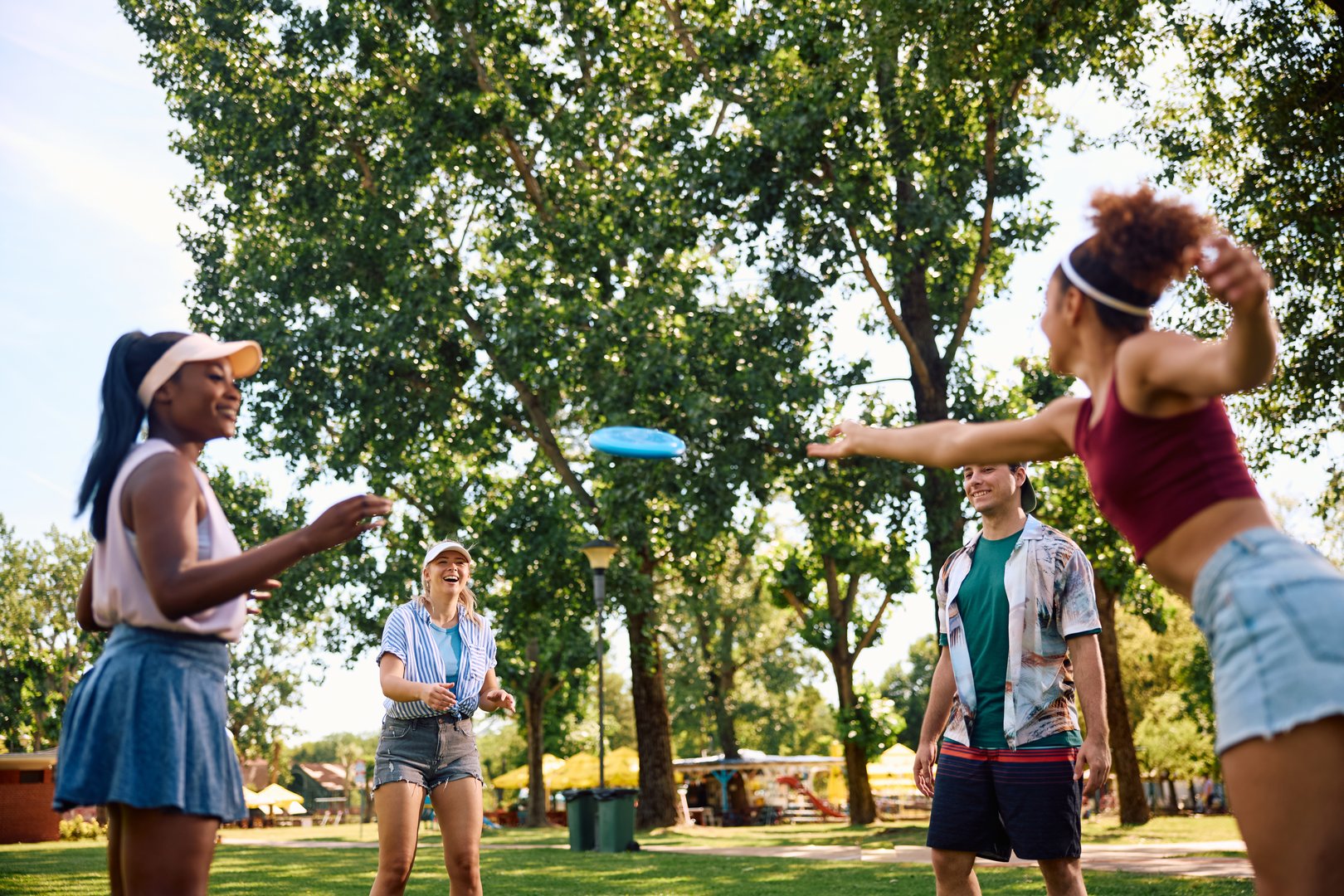 Happy friends having fun while playing with frisbee in the park. Copy space.