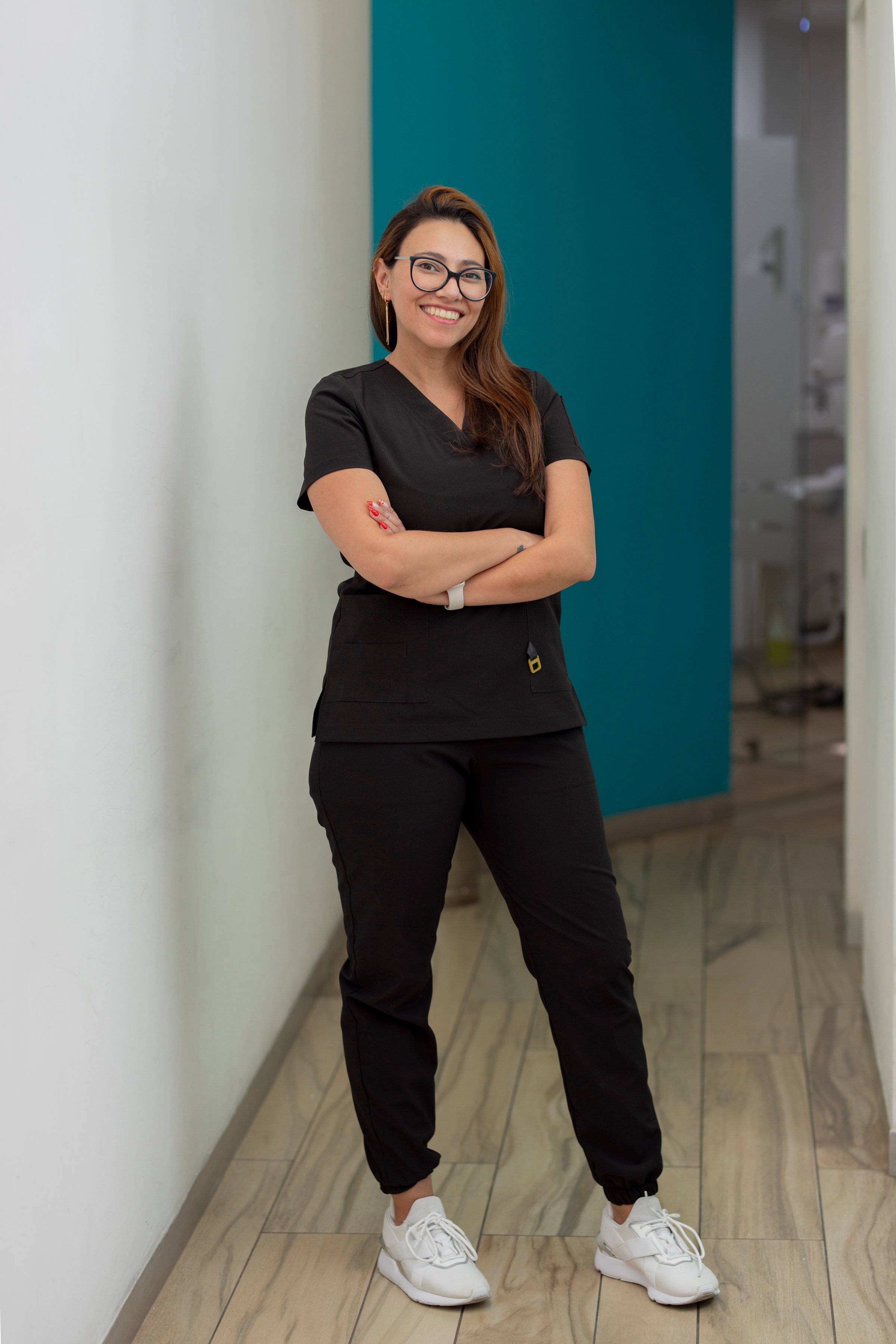 Dentist in a clinic corridor, standing with arms crossed, looking at camera smiling
