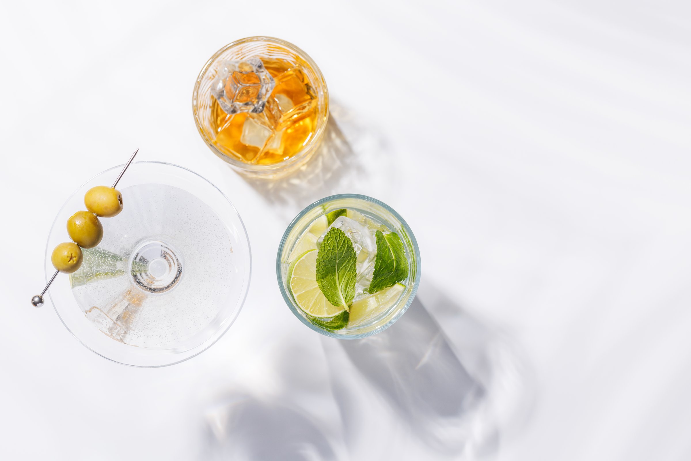 A vibrant display of cocktails, including Spritz, Mojito, and Martini, set against a bright background. A refreshing and colorful celebration of mixology