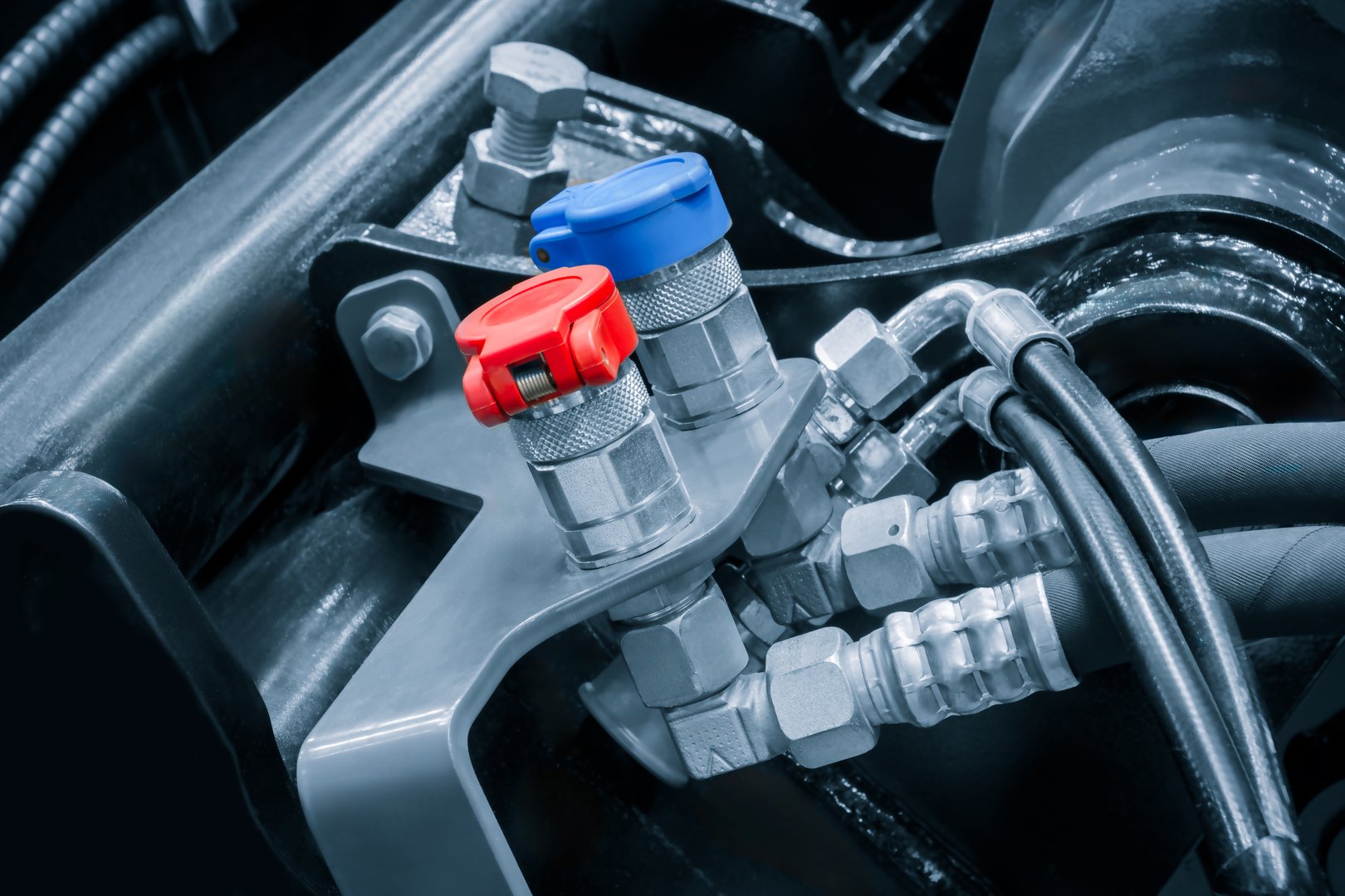 A close up of a car engine with a blue and red cap on a hose. The hose is connected to a black hose  industrial concept background