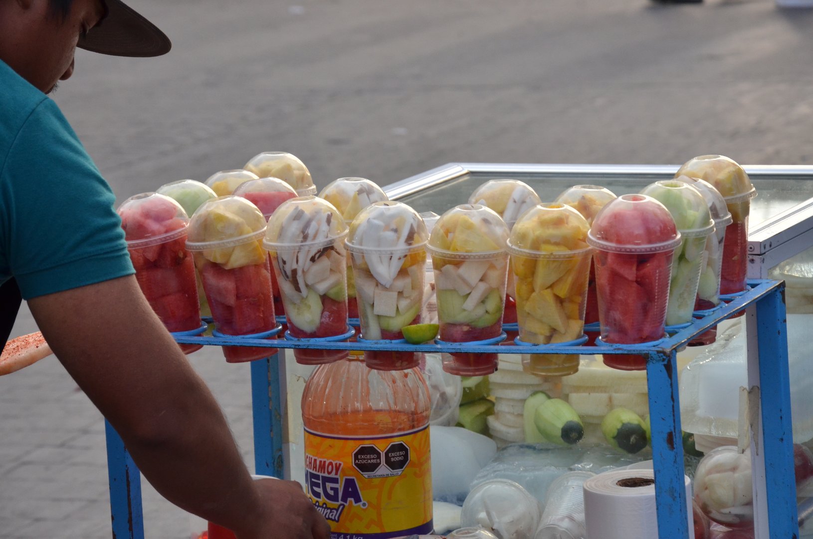 Experience authentic street food culture with this vibrant display of chilled, ready to eat fruit cups and sauces, perfect for capturing lively urban scenes.