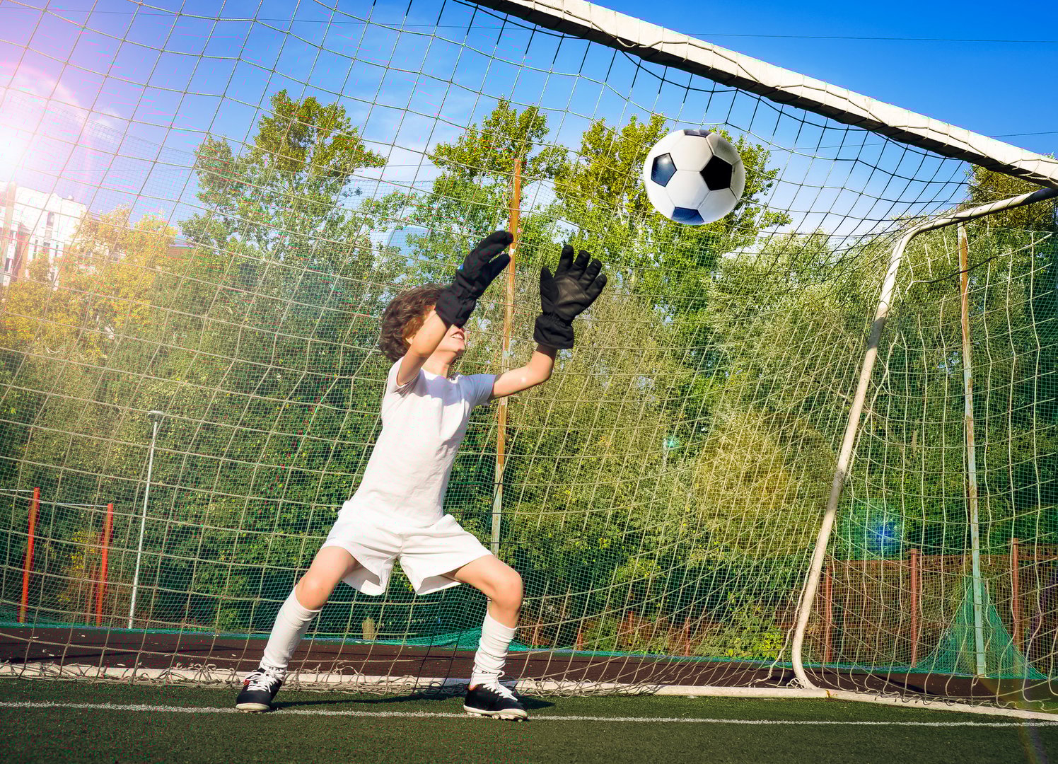 Soccer goalkeeper child in action.Goalkeeper catching the ball. Football soccer game. Boys on the sports field at daytime. Training and practicing.