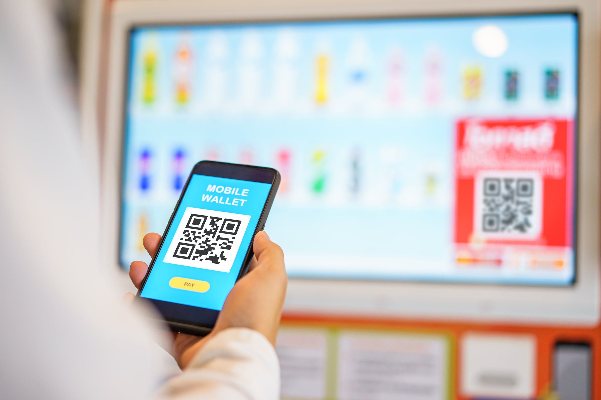 Attractive young male hands using mobile smartphone making payment on vending machine. Mobile wallet payment concept.selective focus