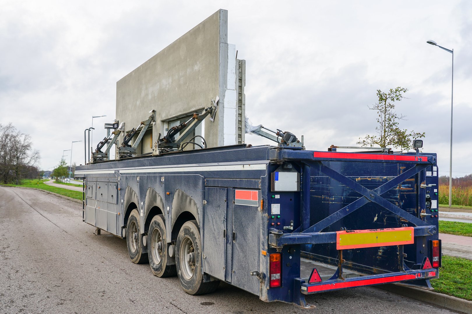 Transportation of reinforced concrete precast wall panels for house construction with a specialized low loader semi-trailer, hydraulically secured load