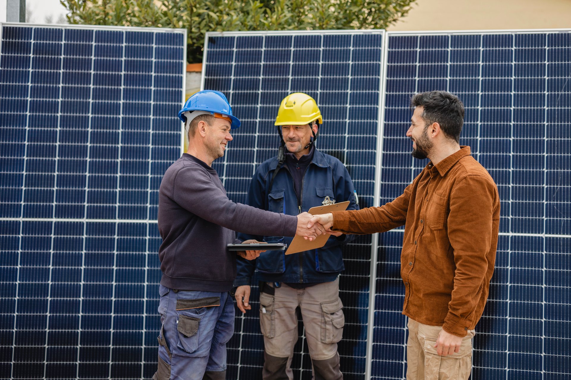 Engineers and customer shaking hands after successful installation of solar panels on a house roof, renewable energy and sustainable lifestyle concept