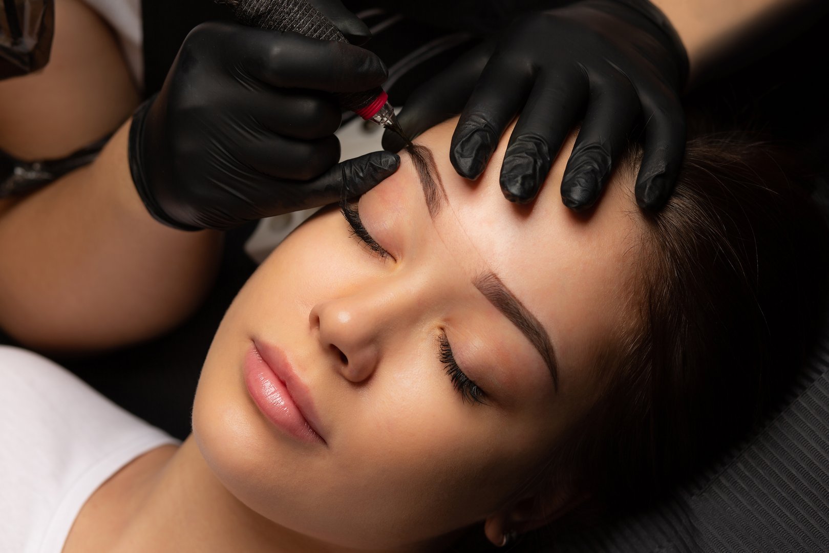 Process of creating permanent brow makeup with a machine at beauty salon