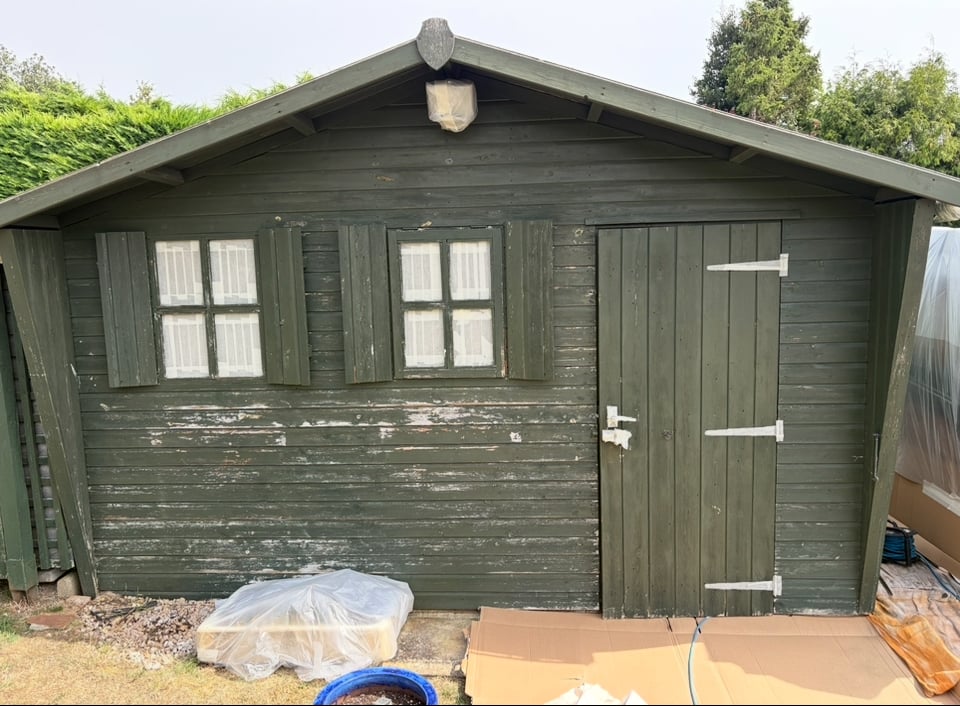 Large green shed before professional painting and restoration