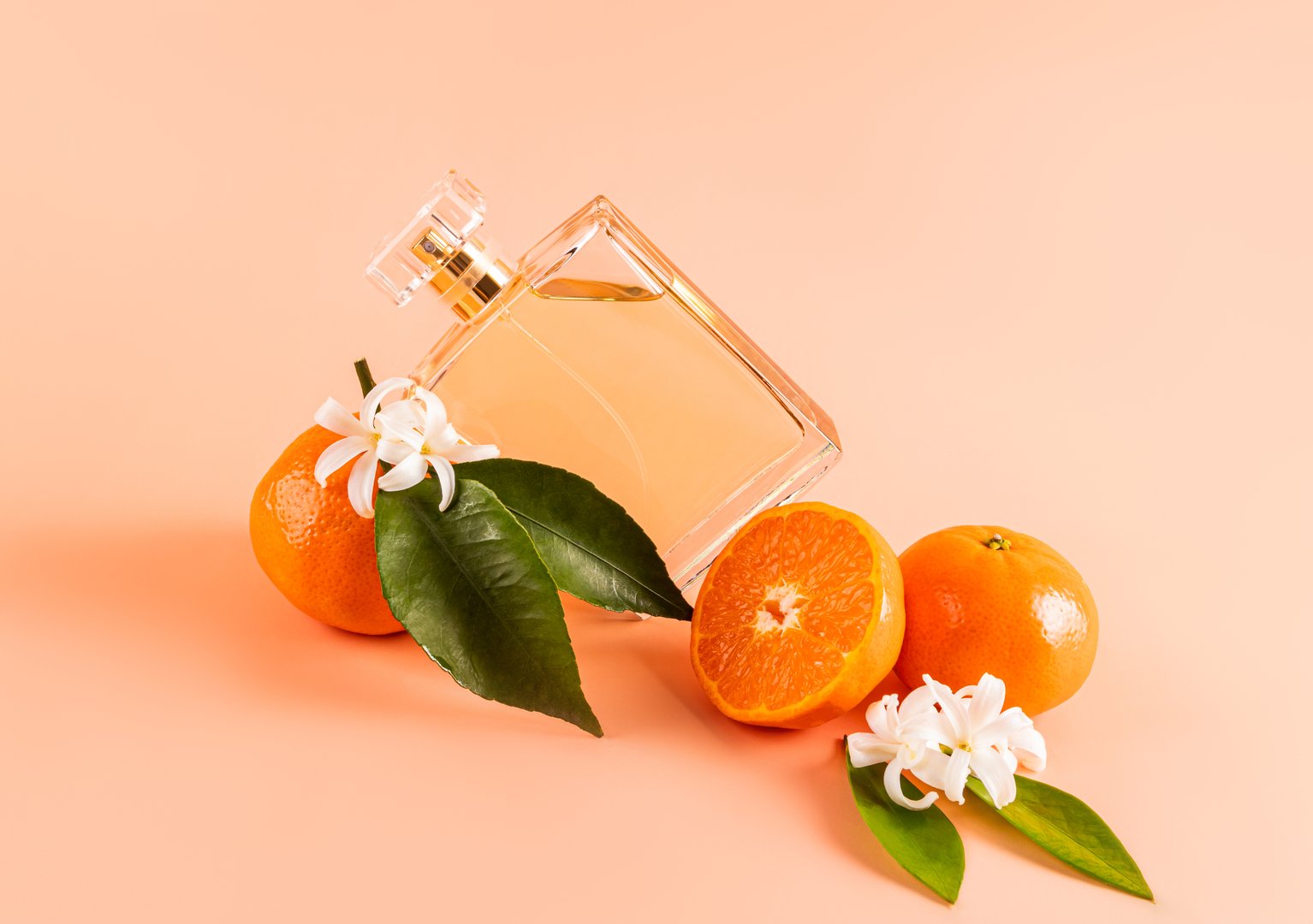 A transparent bottle of cosmetic spray, cologne, citrus-scented product lies on juicy tangerine fruits. product advertising. A blank bottle mockup
