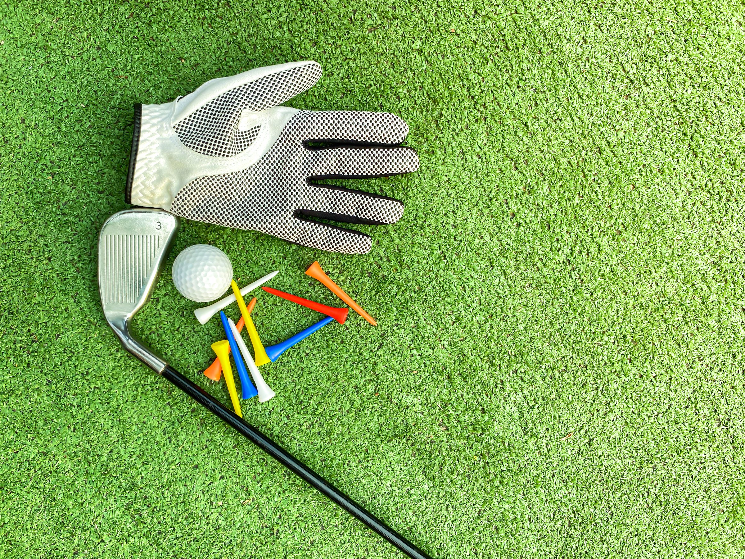 Golf clubs and golf balls with equipment placed on the green grass.