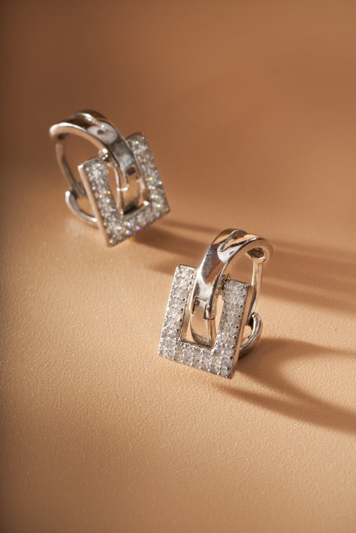 A pair of delicate earrings jewelry on an orange background