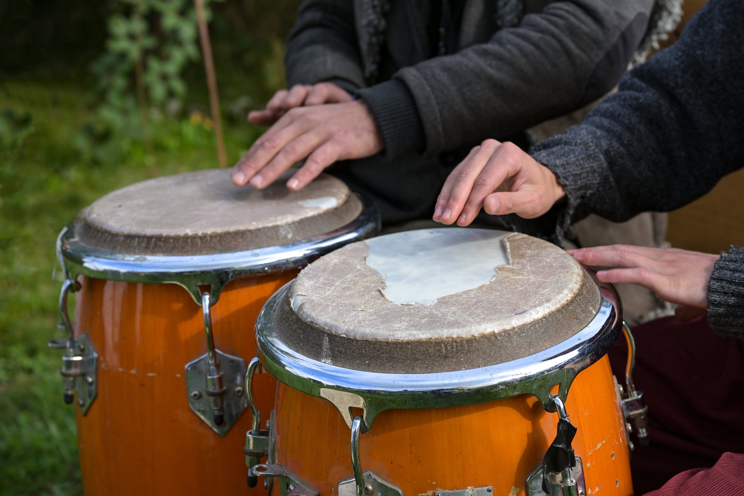 Two musicians playing conga with worn drumskin on an outdoor festival, musical instrument for Latin and Afro-Cuban music, salsa, jazz and more played as hand drums, selected focus, narrow depth of field