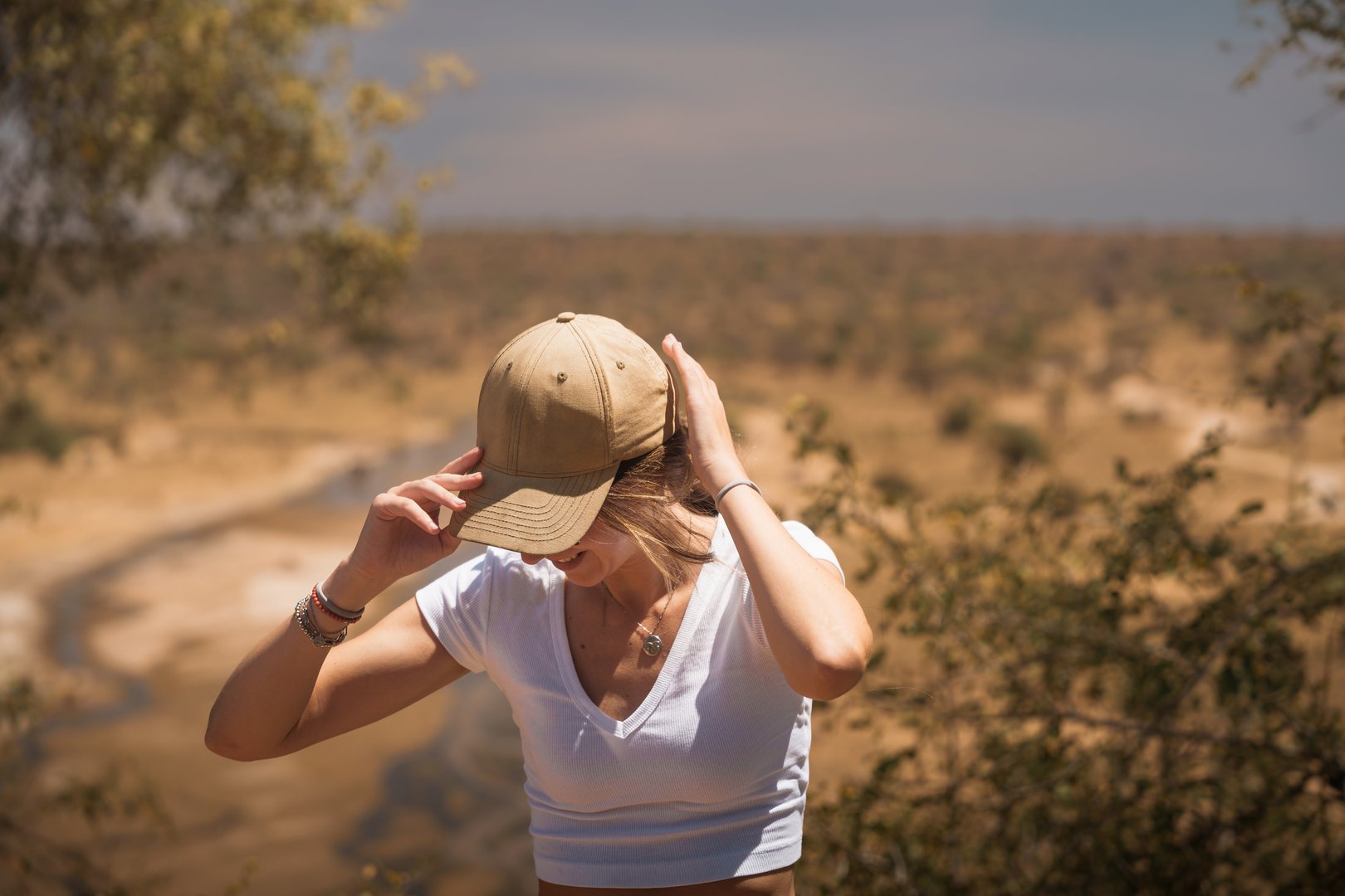 Young woman adjusting her hat while enjoying the view during a safari in tarangire national park, tanzania