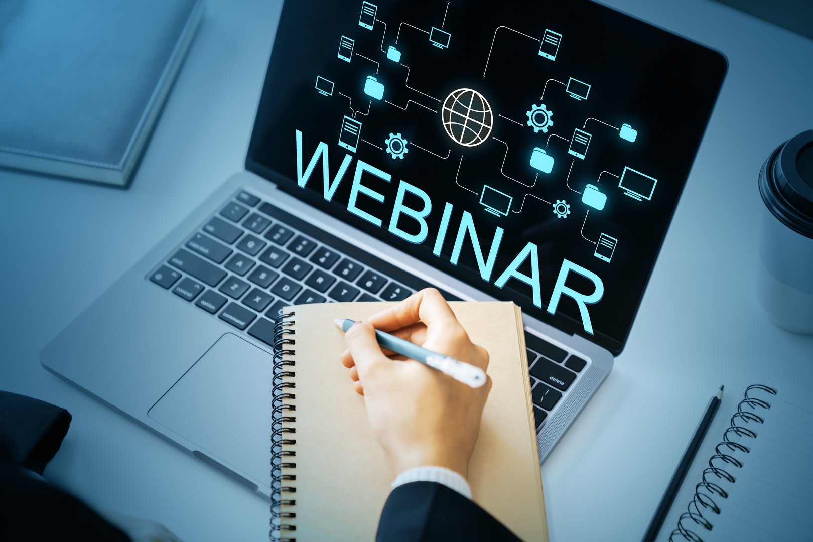 Person writing in notebook during online webinar on laptop screen, futuristic light graphics on dark background, concept of digital learning