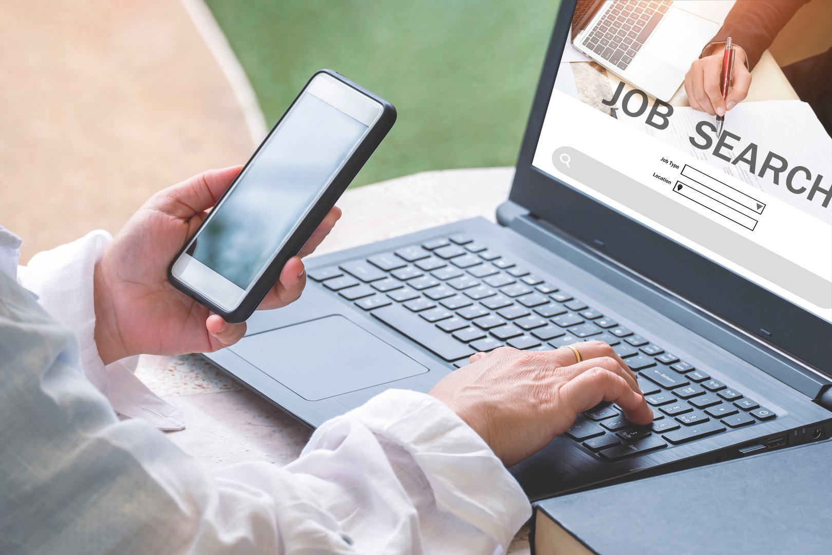Woman hands using smartphone with laptop computer to searching for find jobs vacancies on internet at home, Job search concept