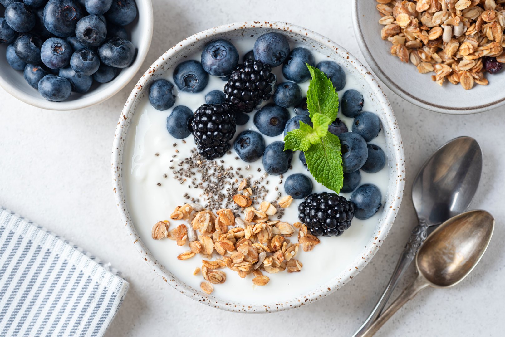 Bowl of greek yogurt with blueberries, blackberries, chia seeds and granola topping. Table top view