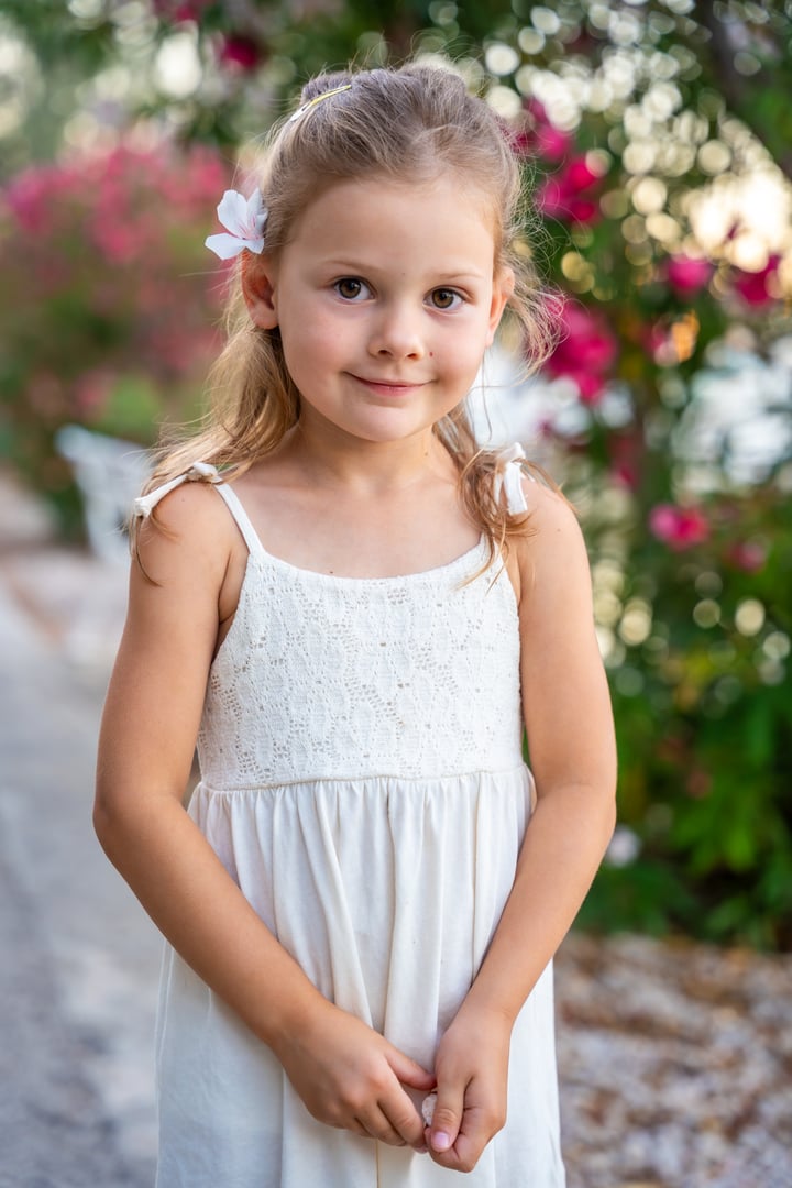 Portrait of little girl in white dress happy smiling on blooming park background in Croatia. High quality photo