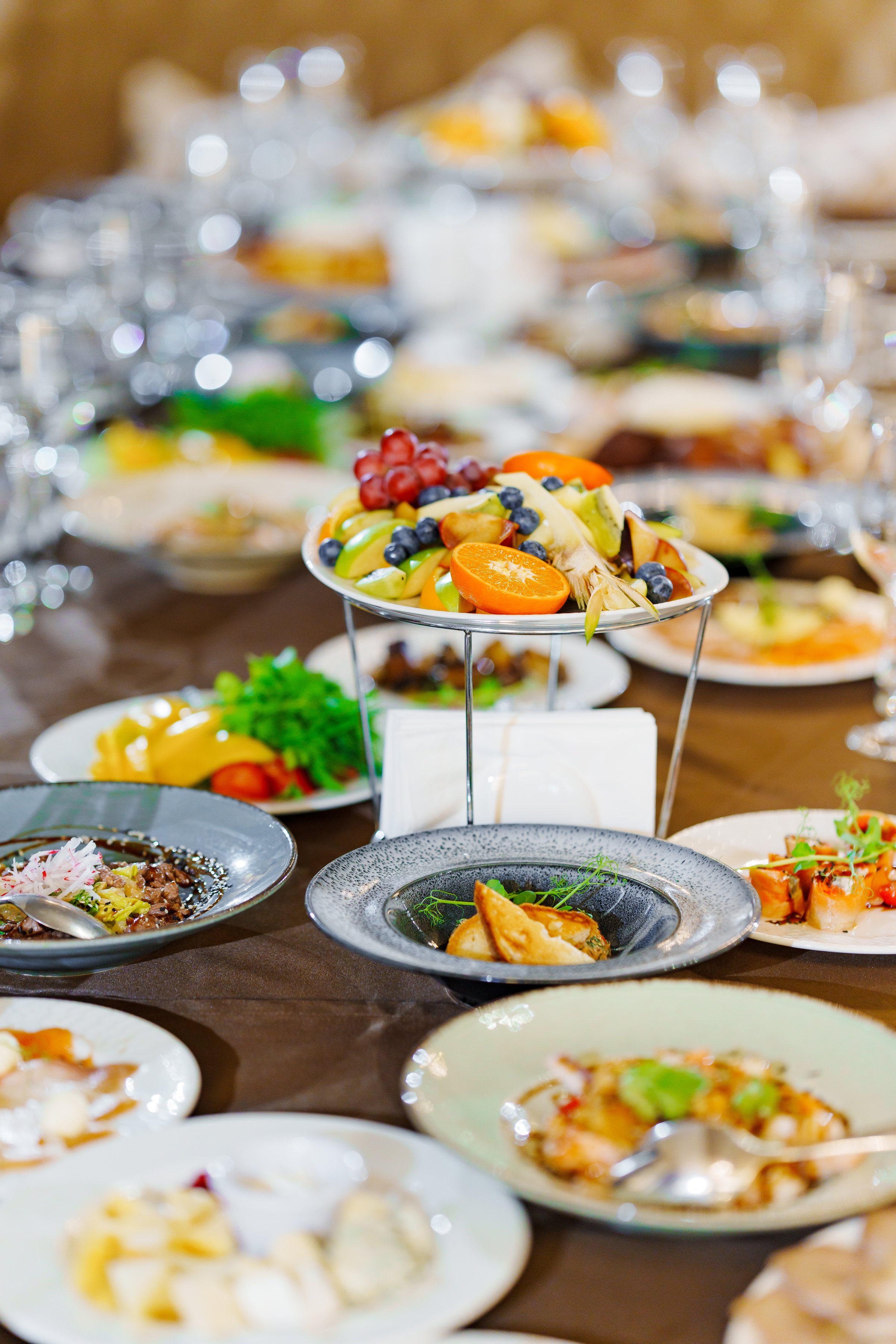 a large served festive table with appetizers. Fruit dish stand in the center of the table.