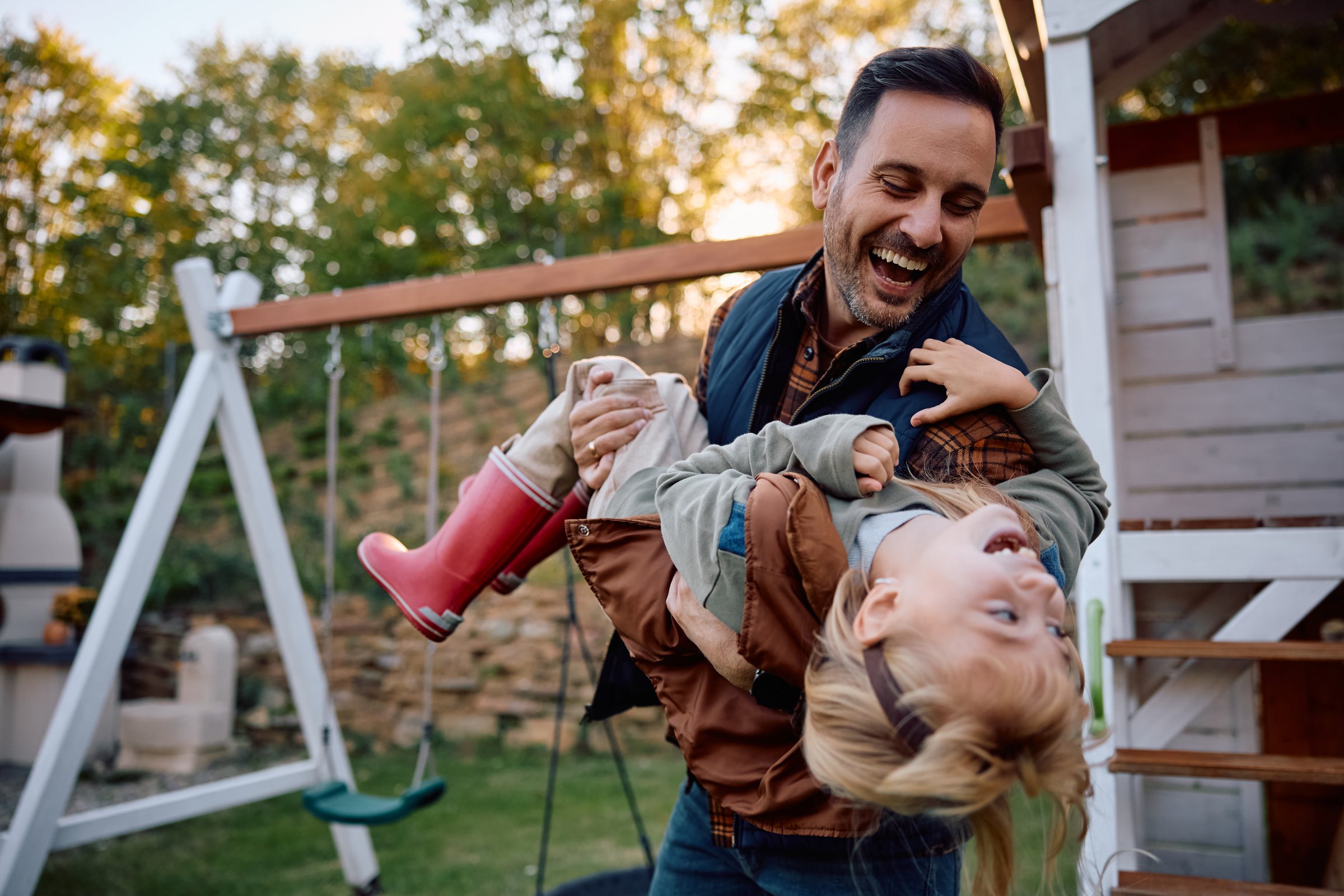 Playful father having fun with his daughter in the park in autumn.