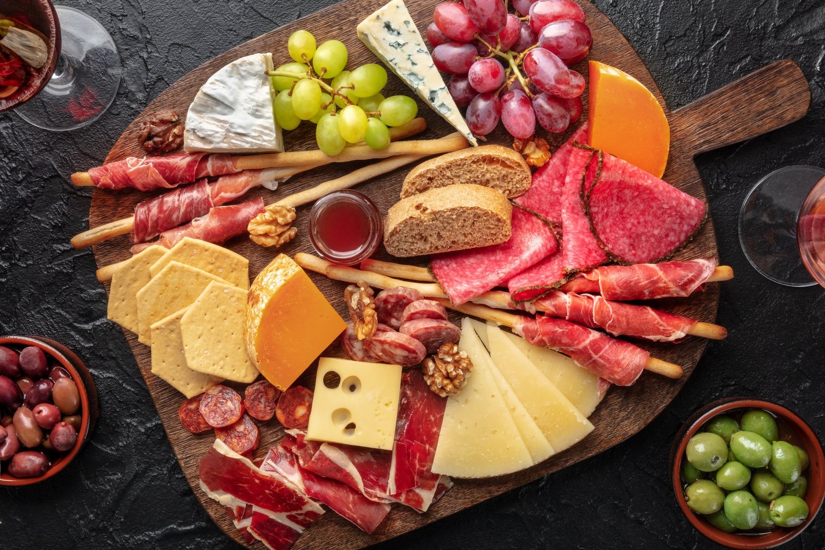 Antipasti or tapas. Charcuterie and cheese board with fruit, overhead shot. Cold cuts and delicatessen, with bread and olives