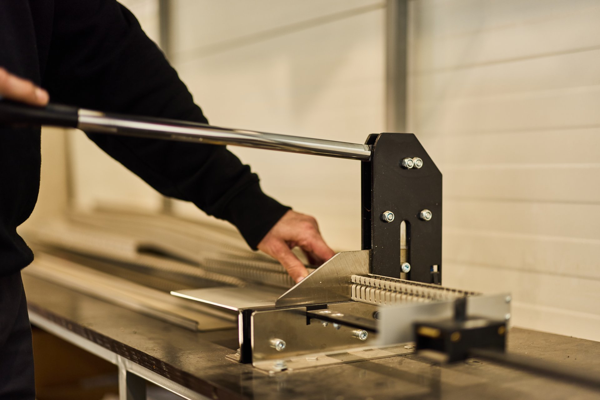 Close-up of metal bending equipment operated by hand in an industrial workshop setting.