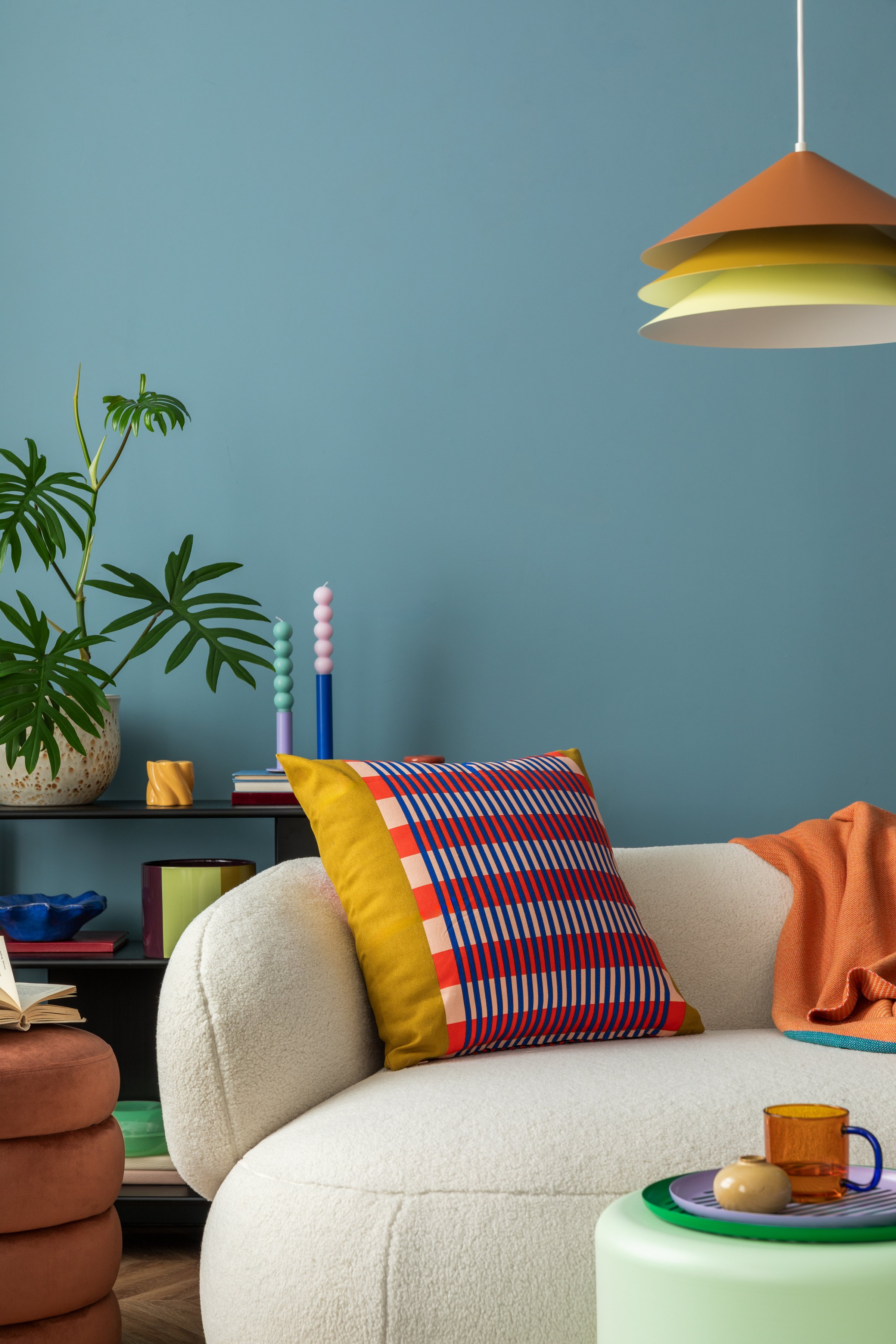 Interior desgin of modern living room interior with colorful decorations and accessories, plants, sofa, coffee table, lamp and plant. Blue wall. Home decor. Template