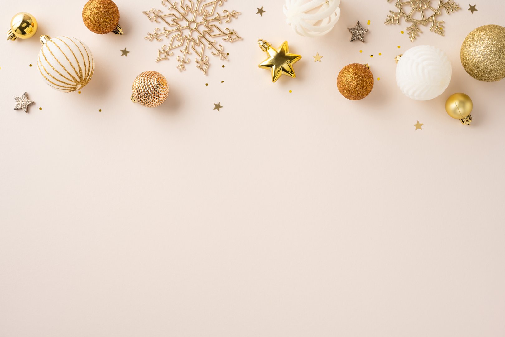 Golden and white holiday decorations, including stars and balls, on a light beige surface