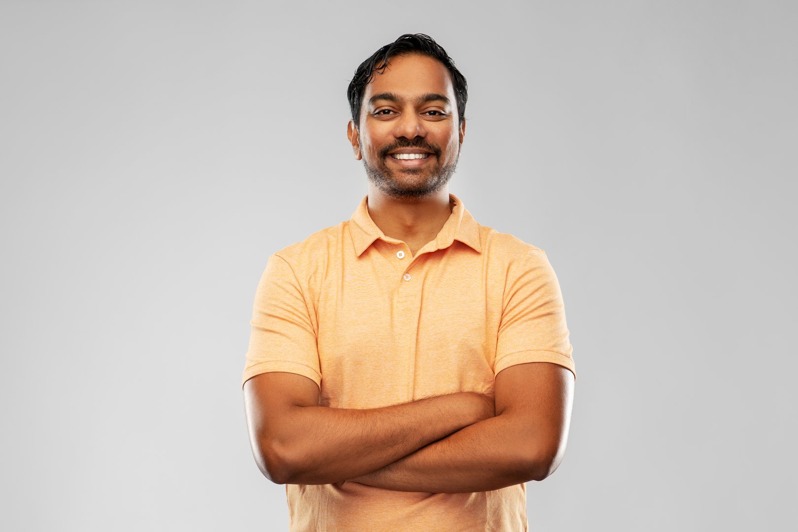 people and furniture concept - portrait of happy smiling young indian man with crossed arms over grey background