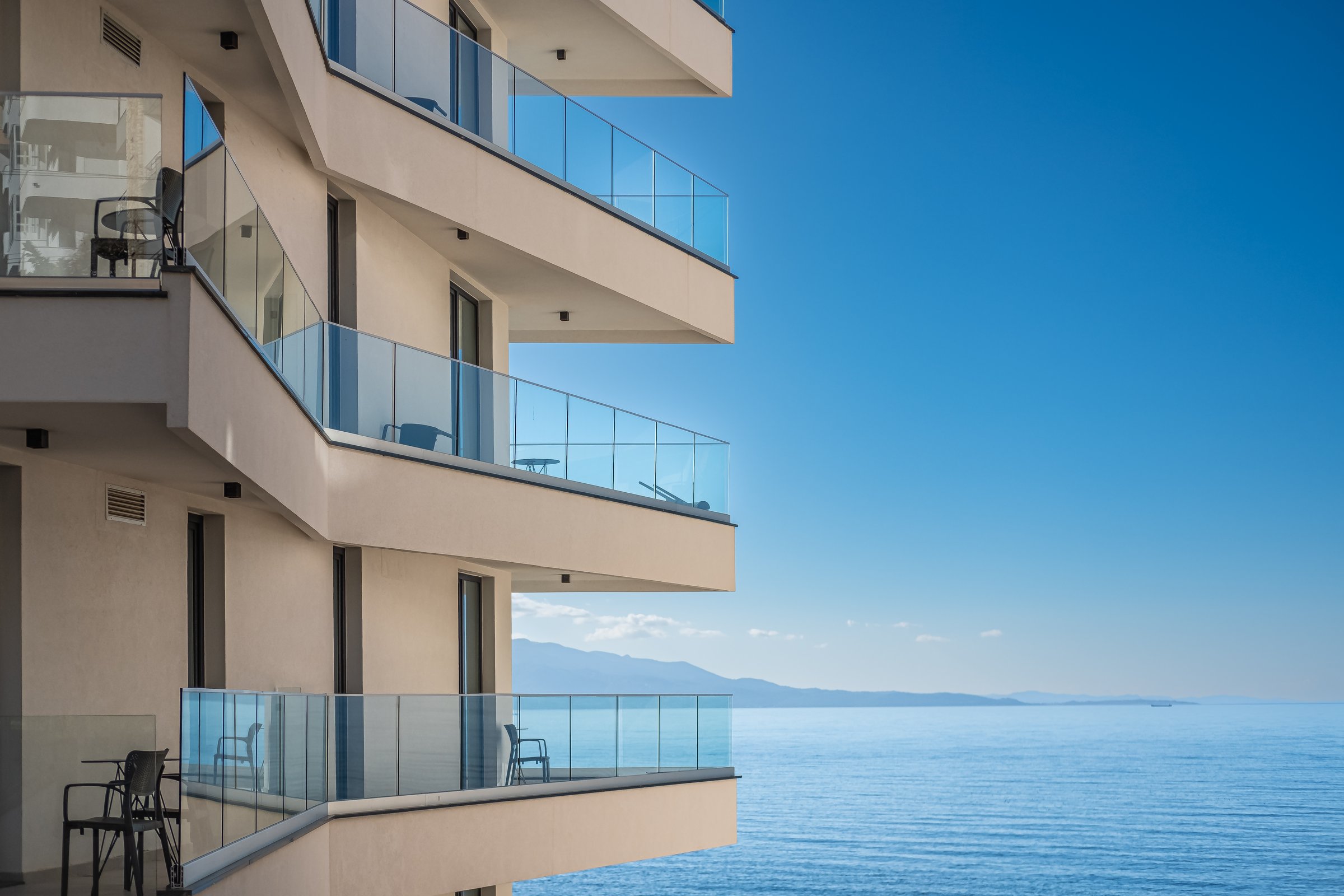 Modern white apartment building with blue sky and sea background. Beautiful modern architecture of the building. Architecture detail Modern facade building with balconies and windows