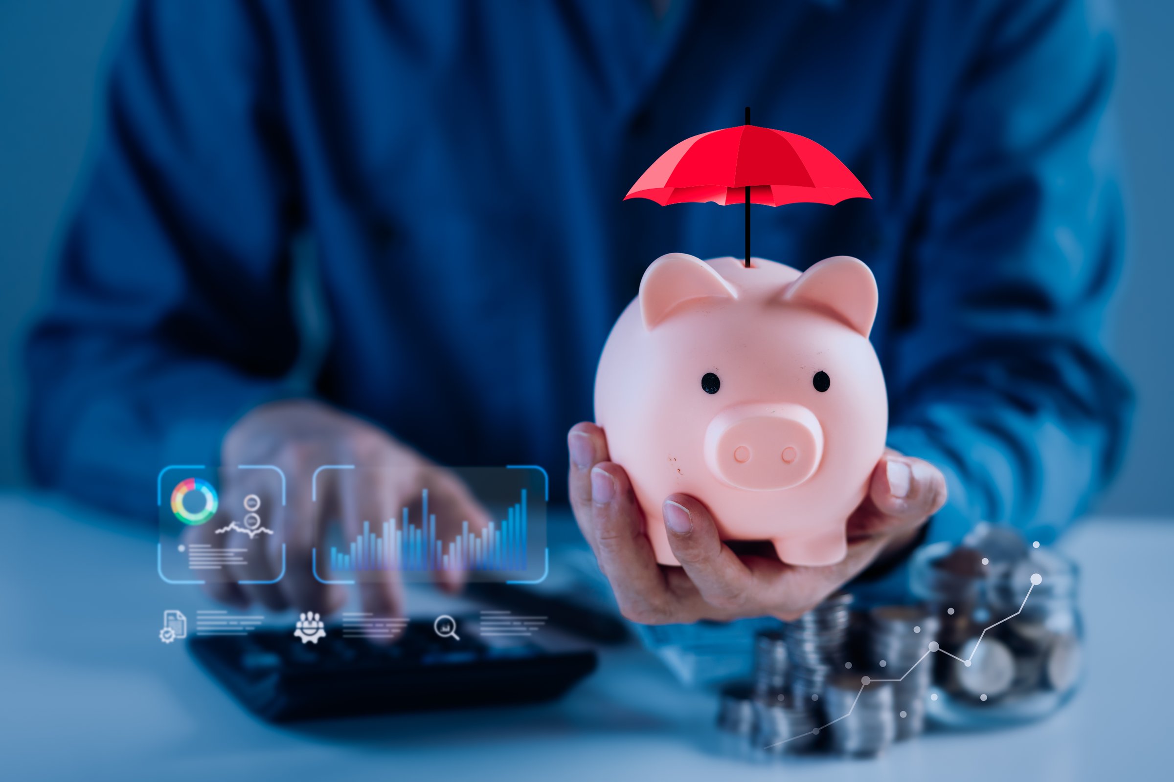 A person holds a piggy bank topped with a red umbrella, symbolizing the importance of saving and protecting finances for future growth and success